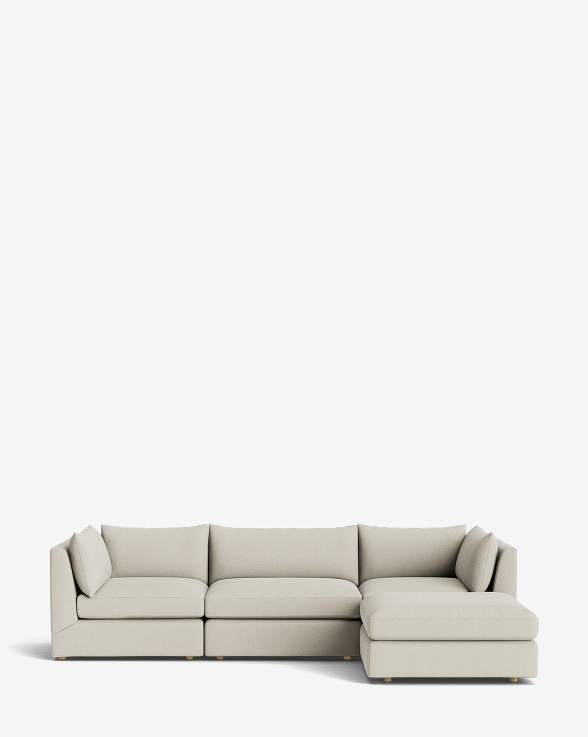 The Vivienne Modular Sofa with Ottoman is a modern, light beige sofa with clean lines, low backrests, and a handmade right-side chaise lounge, displayed against a plain white background by McGee & Co.