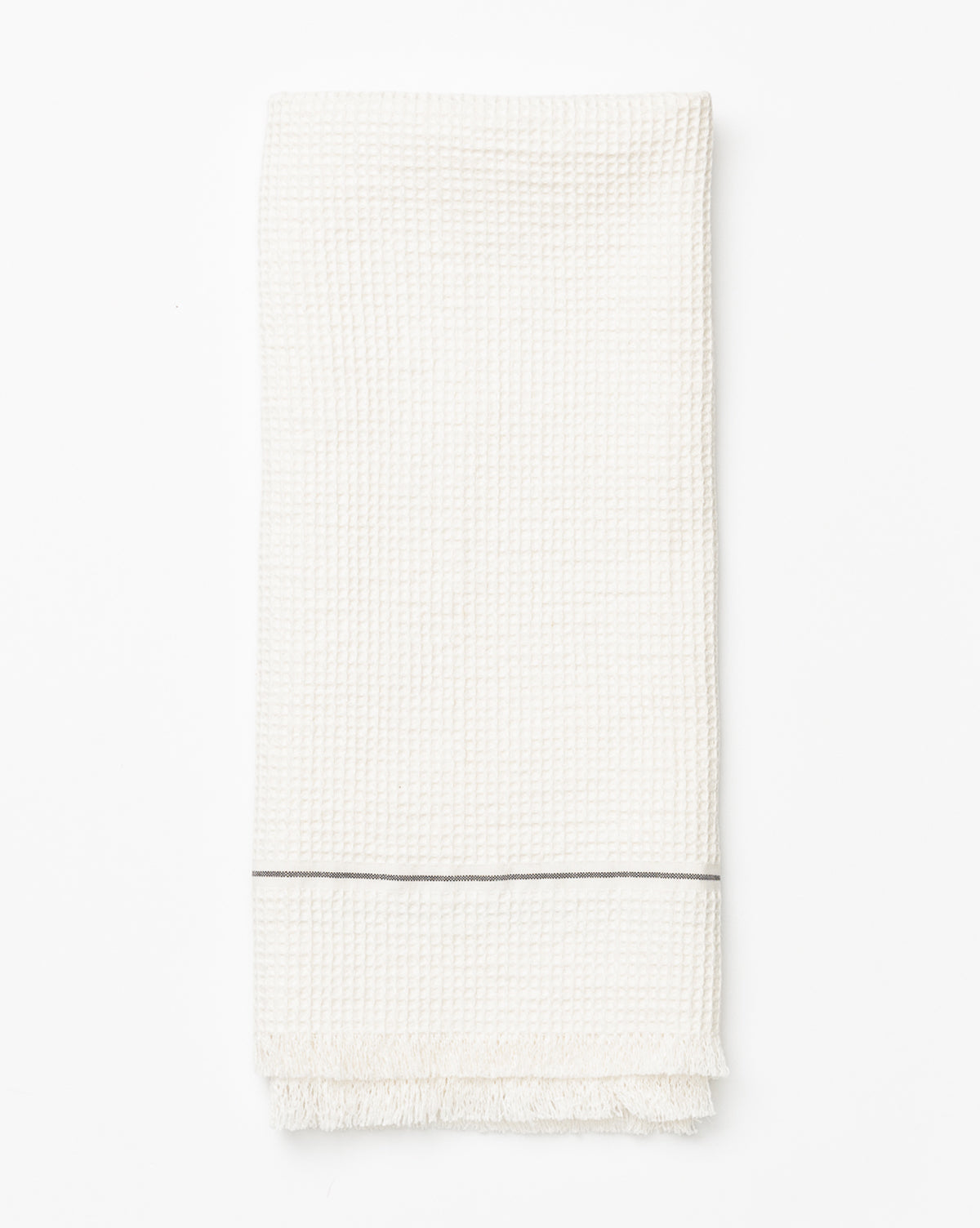 The Waffle Hand Towel features a subtle textured pattern, a thin gray stripe near one end, and short fringes along the edge. Neatly folded and displayed on a white background, it’s perfect for enhancing your kitchen decor, by McGee & Co.