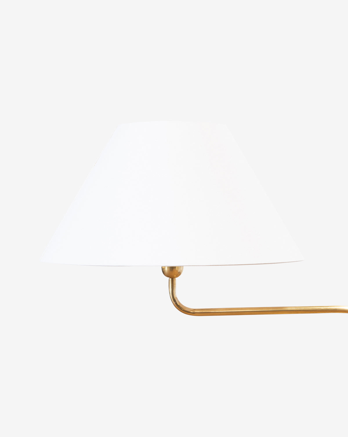 The Wainwright Swoop Floor Lamp features a white cone-shaped shade and a brass arm extending right, shown against a plain white background, by McGee & Co.