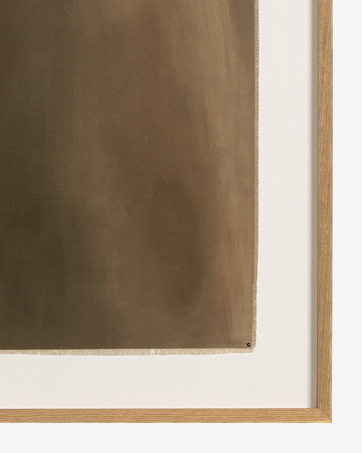 A close-up of A Hint of Glimmer by Melody Joy McMunn shows its earth-toned, abstract surface with subtle gradients, framed in white oak and set off by a white mat board along the right and lower edges.