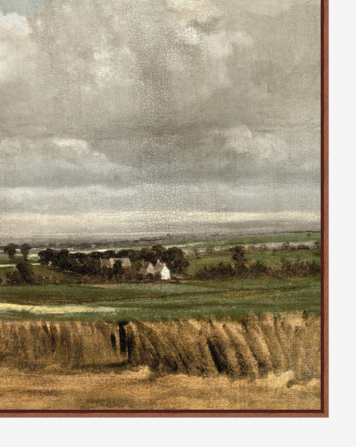 The Wheatfield giclee print shows a wide green field with distant trees and white houses beneath a cloudy sky, all within a brown frame, by McGee & Co.