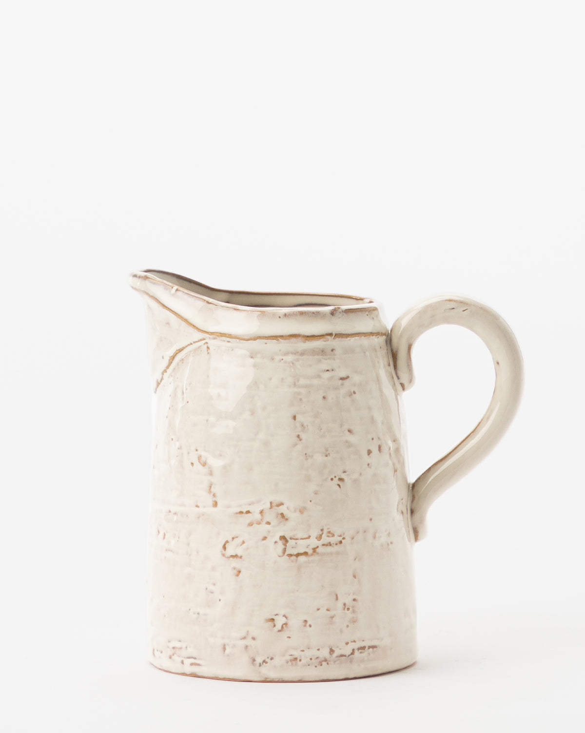 The White Stoneware Pitcher features a cream color, textured rustic surface, and curved handle, shown against a plain white background, by McGee & Co.