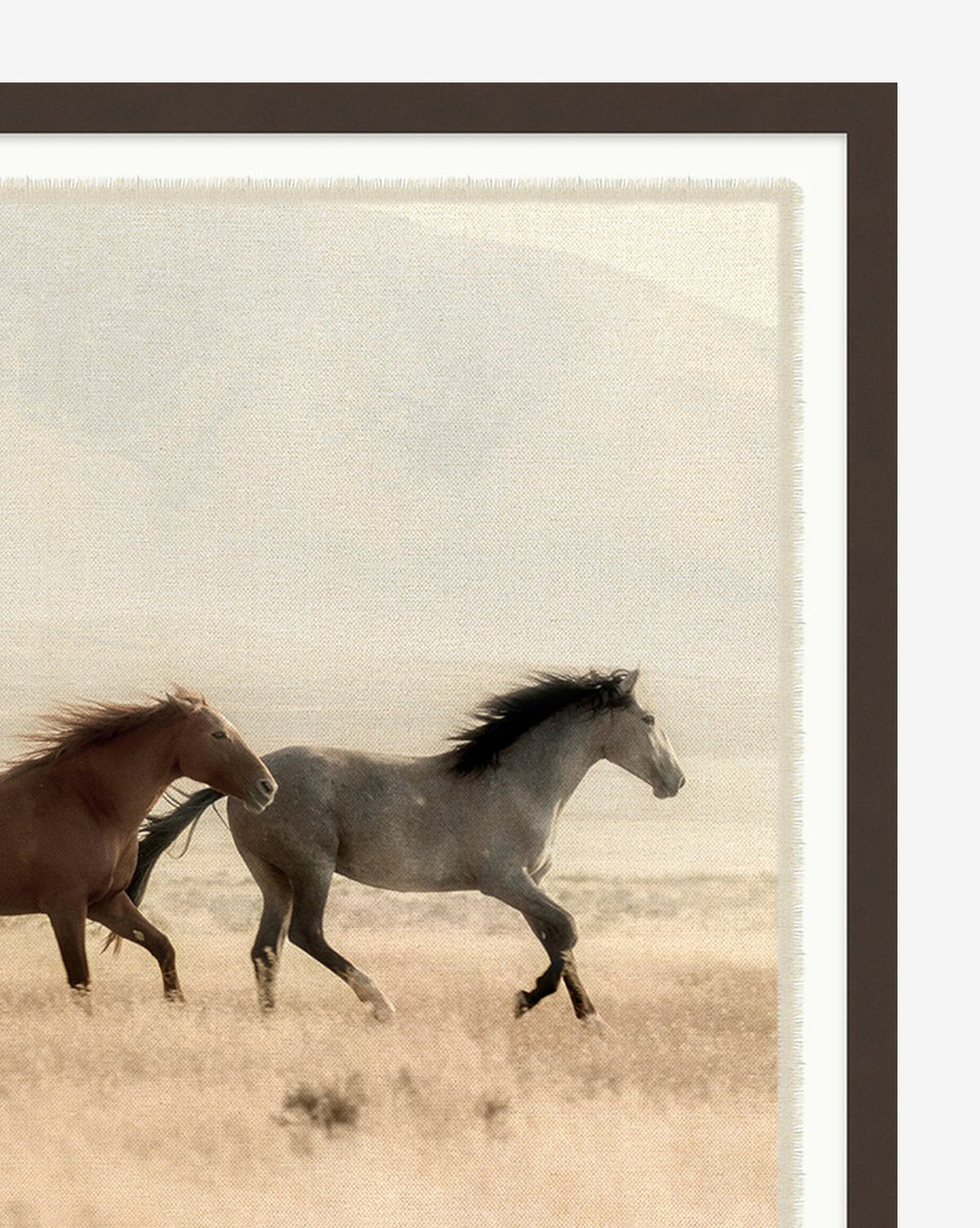 Wild Horses features a brown and a gray horse running together in a grassy field with mountains behind. This nature wall art comes in a dark brown frame, ideal for enhancing your horse decor.