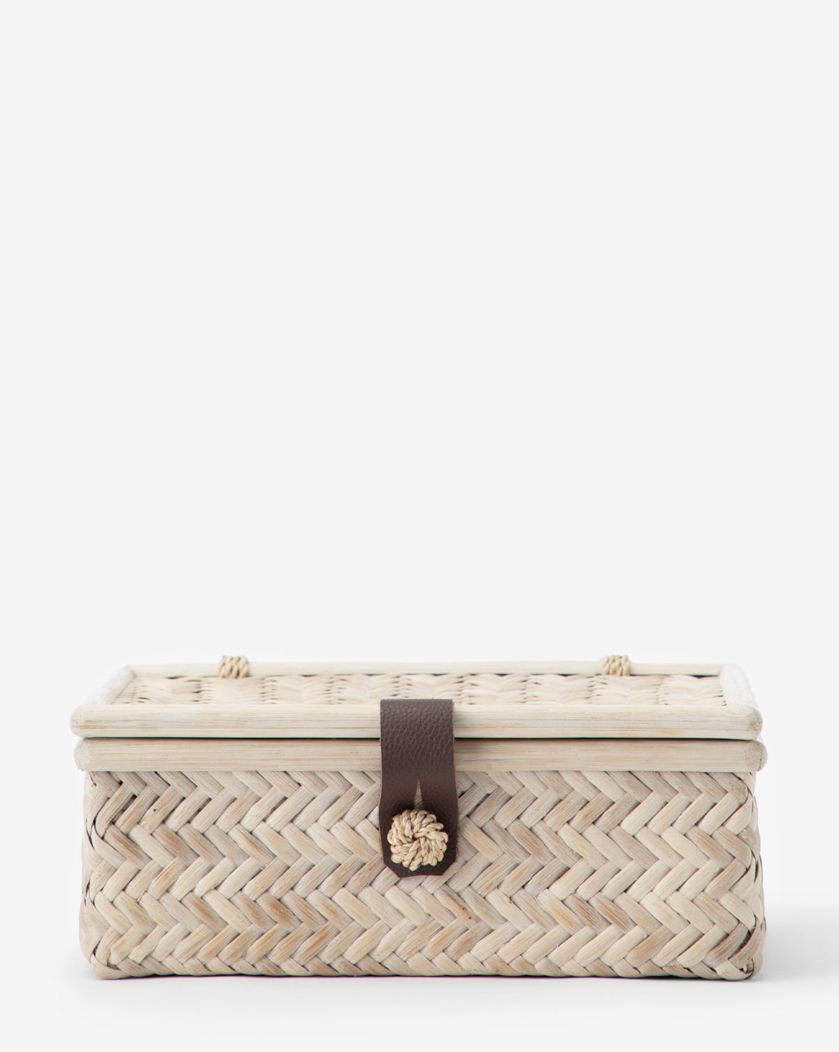 The Winnie Wicker Box is a rectangular abaca fiber box with a lid, dark brown strap, and decorative knob closure at the center, shown against a plain white background.
