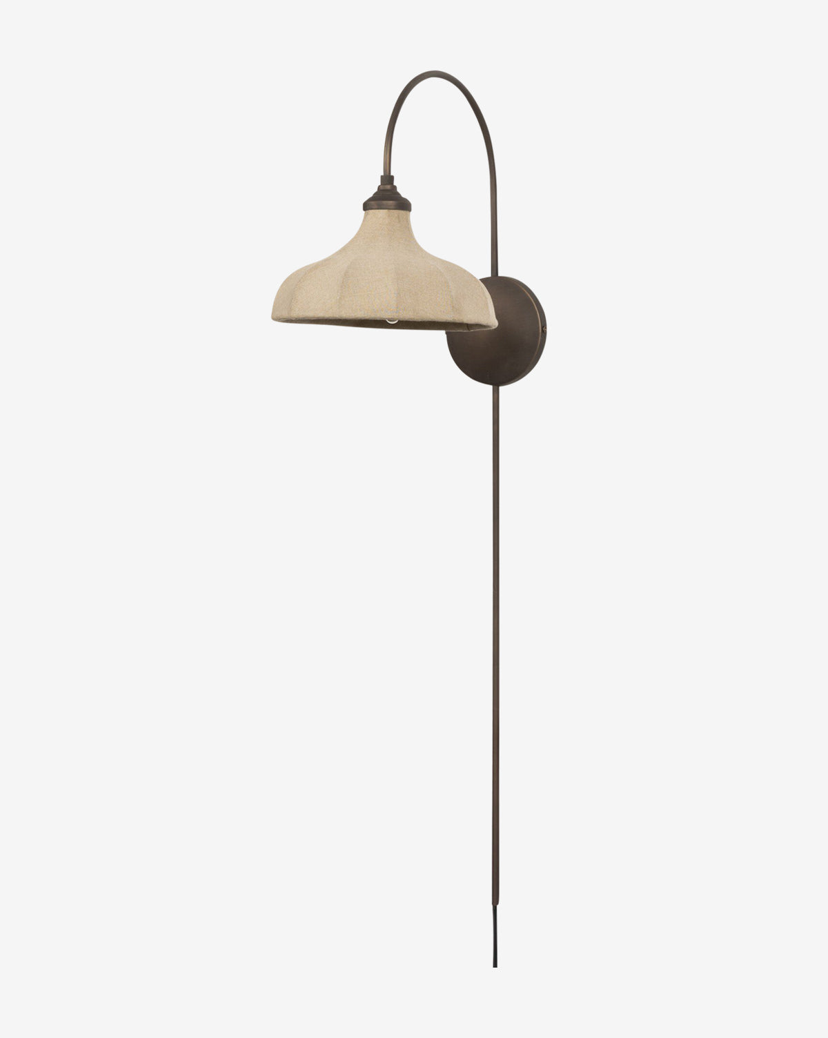 The Winslet Sconce by Four Hands is a wall-mounted brass light with a curved metal arm, wide beige linen shade, dark round base, and long vertical rod. This plug-in sconce stands out against a plain white background. McGee & Co.