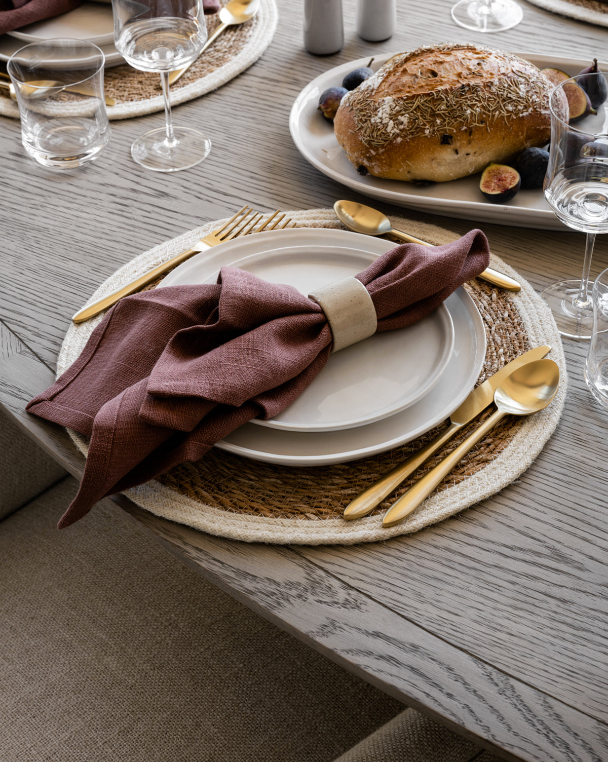 A set dining table showcases the Aiden Side Plate (Set of 4), gold cutlery, a mauve napkin in a ring on a woven placemat, with glasses and a platter of rustic bread and figs nearby, by McGee & Co.