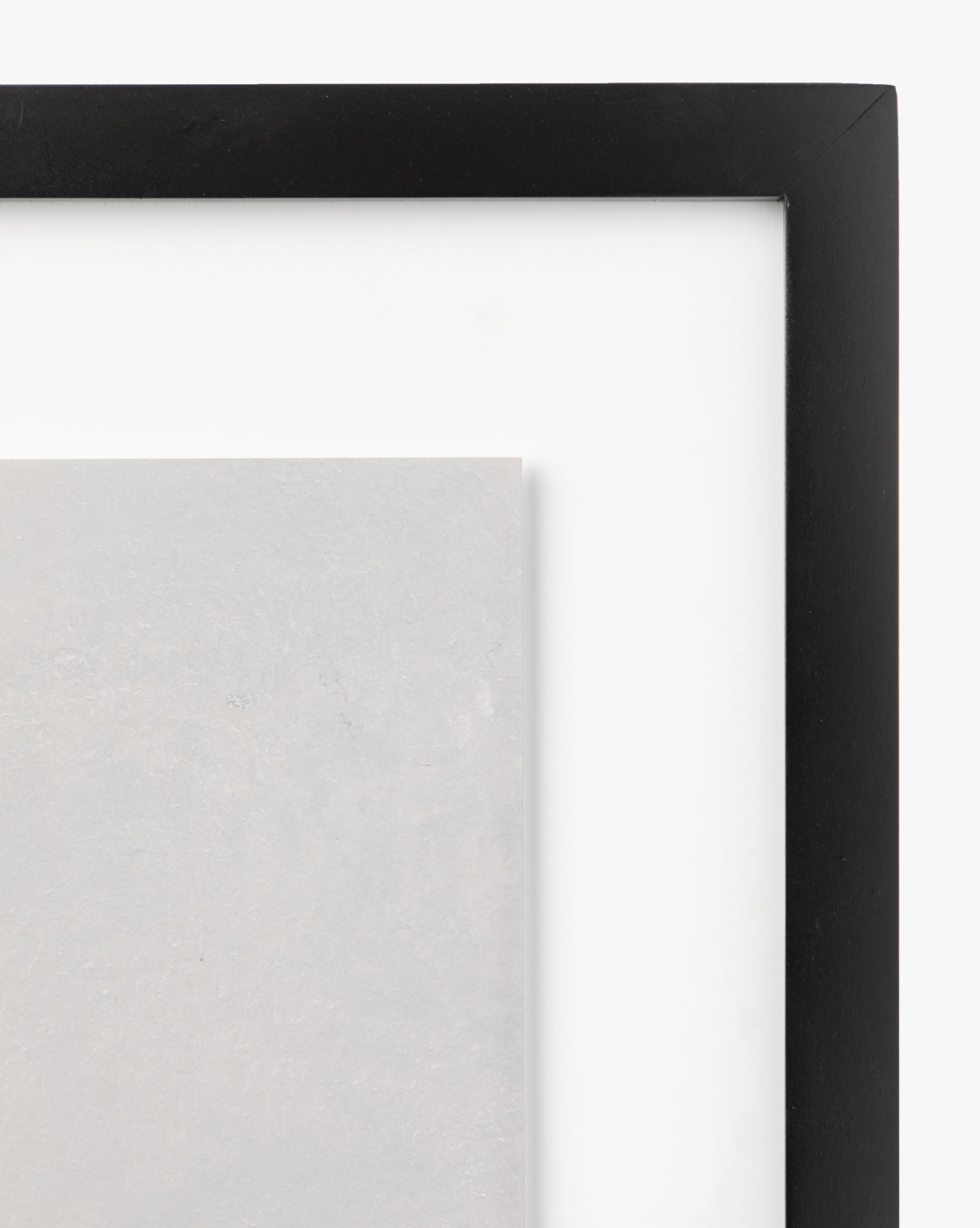A close-up of the corner of a black picture frame with a white mat, showcasing Woodbury by Dan Hobday, a gallery-quality light gray artwork. The background is plain white.