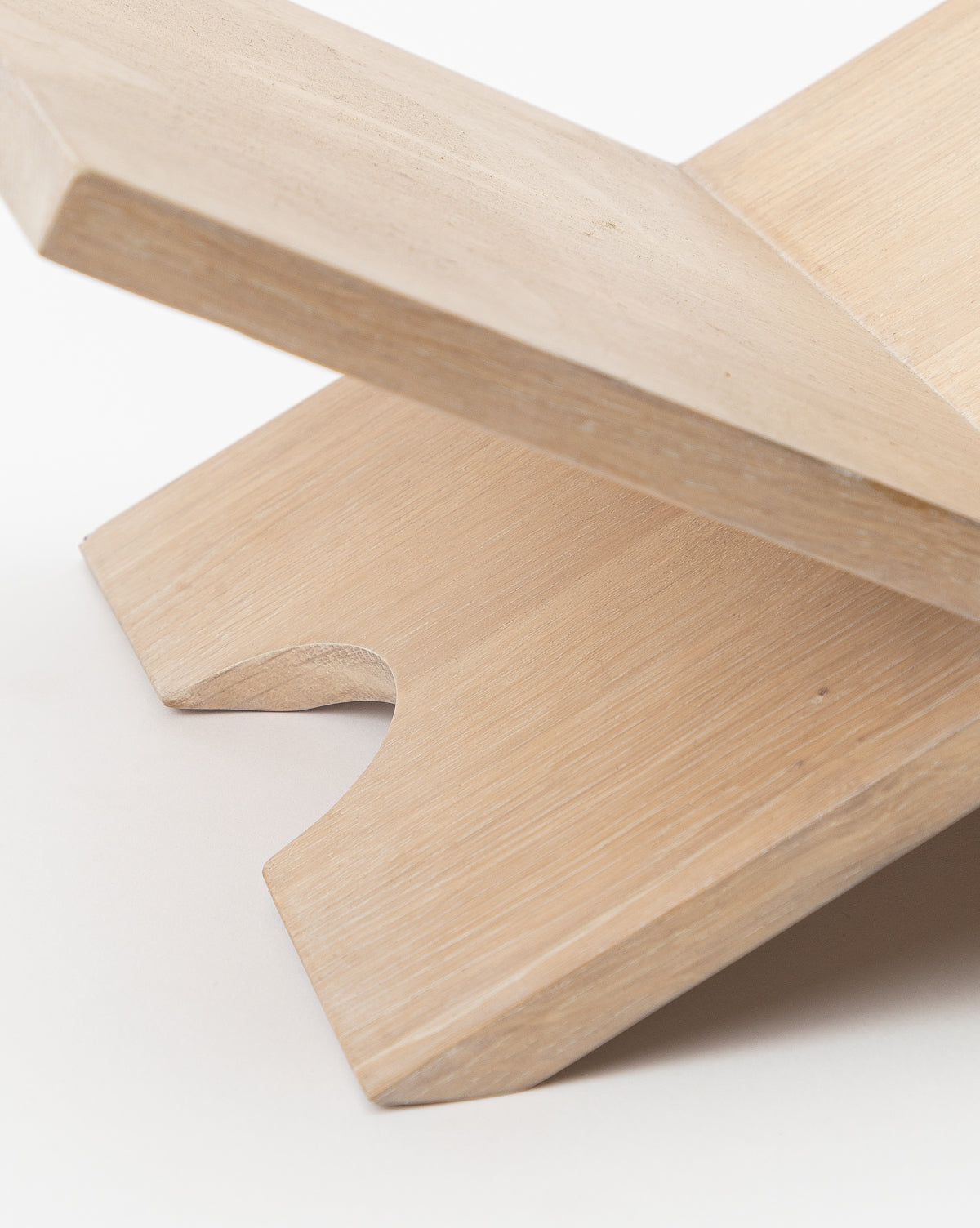 Close-up of the Wooden Book Display in light oak, featuring two flat interlocking panels that form an X shape. Smooth edges and a curved notch add to its functional and stylish design, all set against a plain white background.