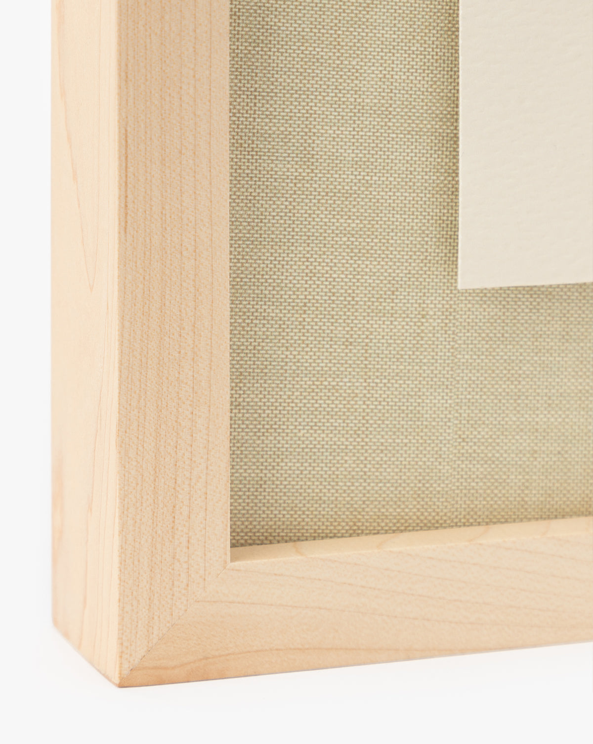 Close-up of the Woof light wood picture frame with its smooth finish, beige textured fabric backing, and a white mat—ideal for displaying fine art prints or framed wall art, by McGee & Co.
