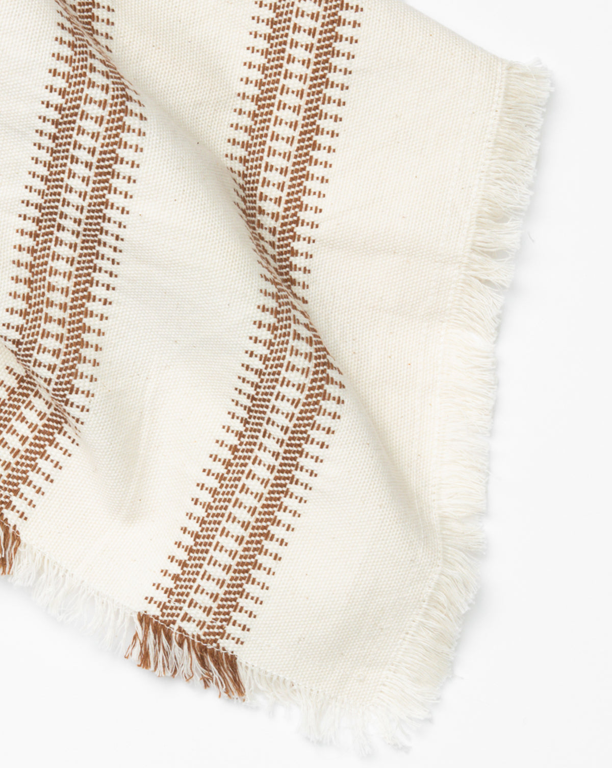 The Woven Stripe Tea Towel is a cream cotton kitchen towel featuring brown geometric stripes and fringed edges, shown on a white background, by McGee & Co.