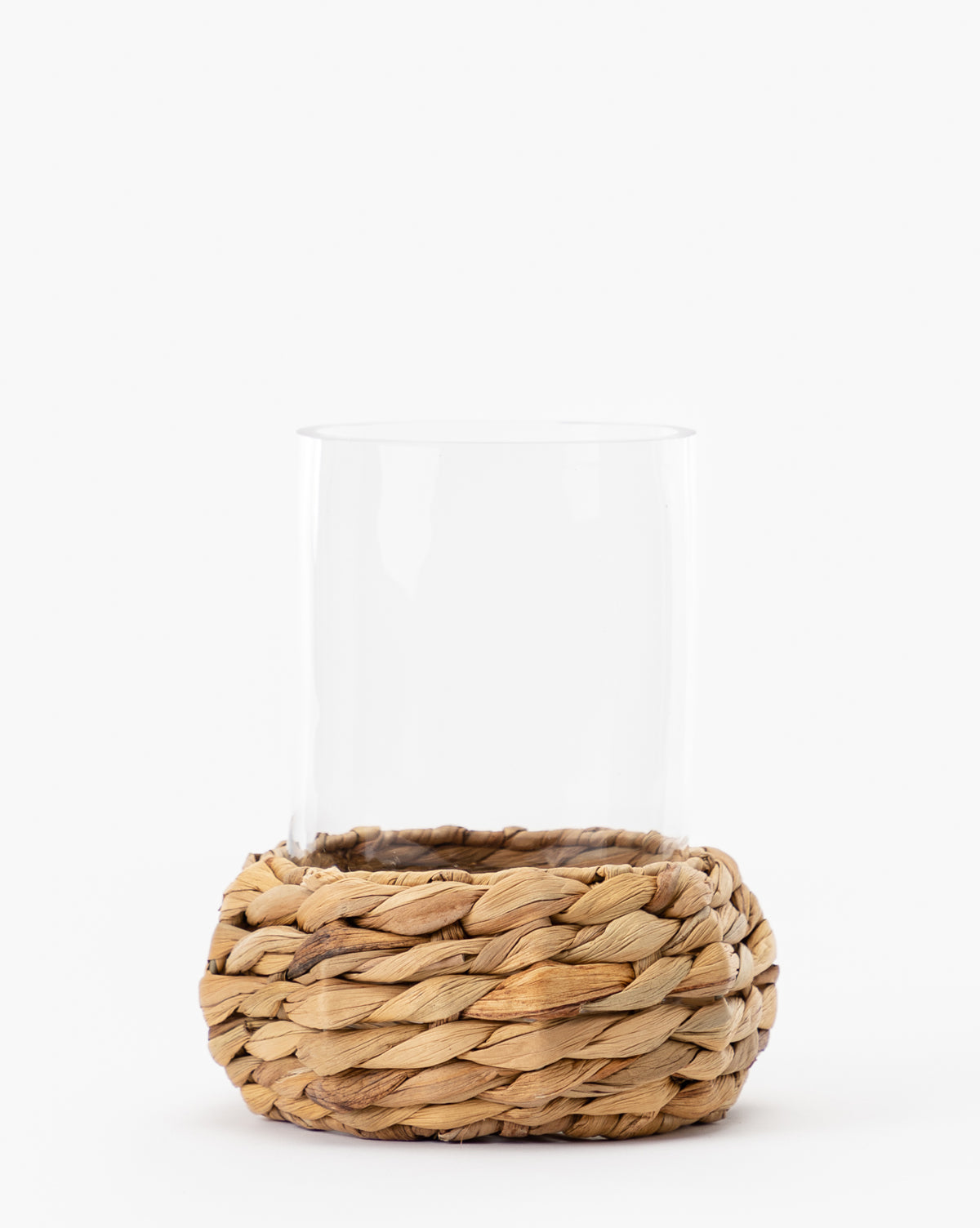 The Woven Hurricane features a clear glass tumbler in a sturdy, natural rattan holder, making it perfect for candle displays and stylish décor accents.