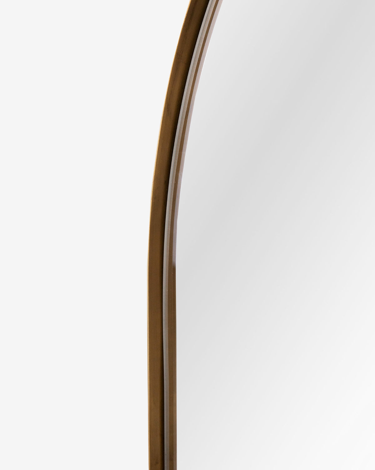 Close-up of the Wylie Arched Mirror’s rounded wooden frame against a white background, showing part of its shatterproof glass on the right side, by McGee & Co.