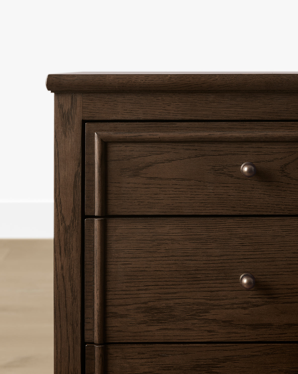 Close-up of the left side of the Yorkshire Dresser in English oak finish, featuring three drawers with round metal knobs, set against a white wall and light wood floor—perfect for stylish bedroom storage, by McGee & Co.