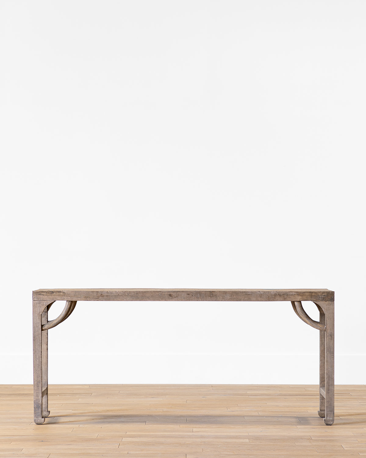 The Youngman Console Table, featuring a minimalist wood design with clean lines and square legs, stands on a light wood floor against a plain white wall by McGee & Co.