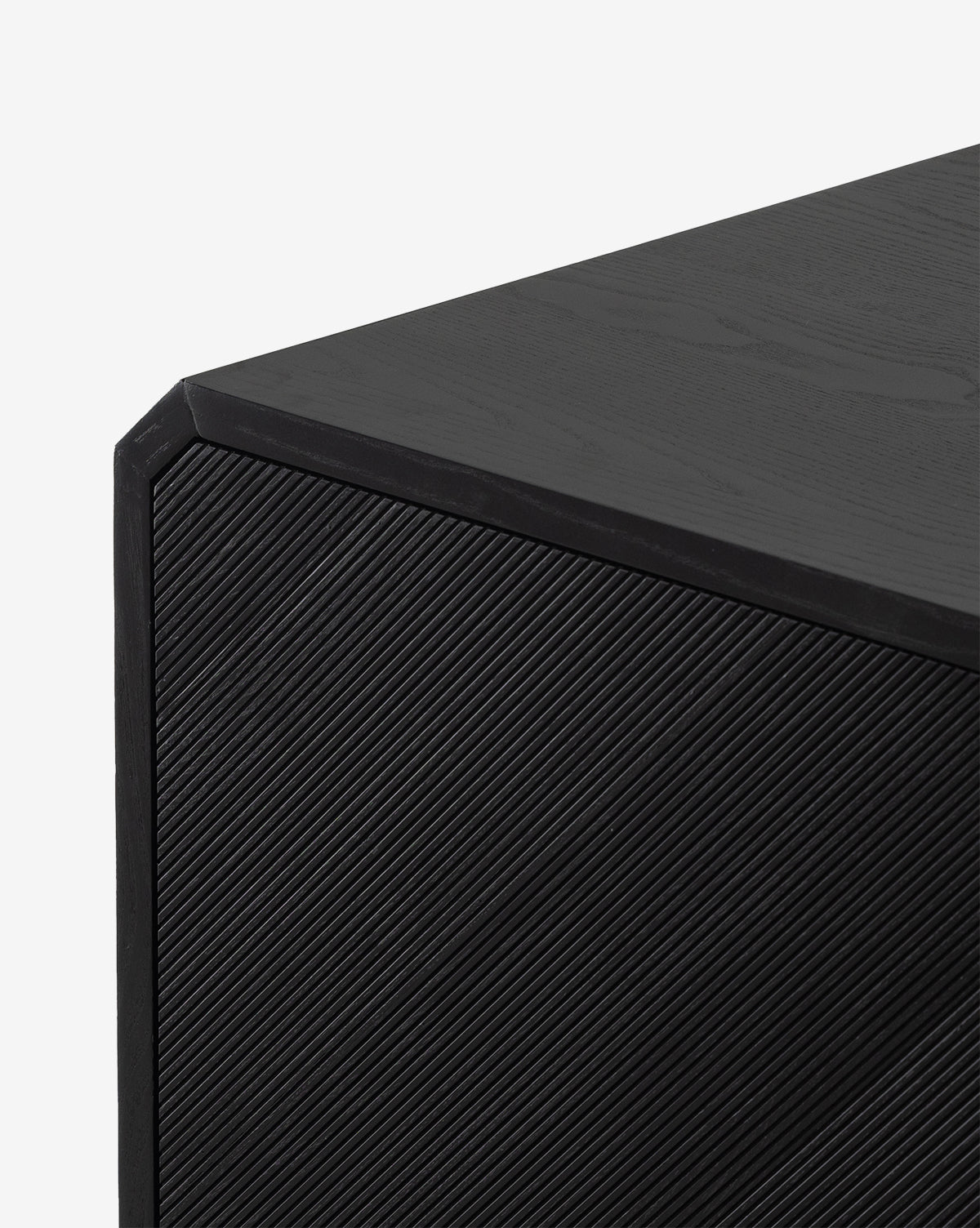 Close-up of the Ziggy Sideboards corner, showcasing its modern black ash veneer with textured diagonal lines on the front panel and a smooth top—ideal as a sleek storage solution, by McGee & Co.