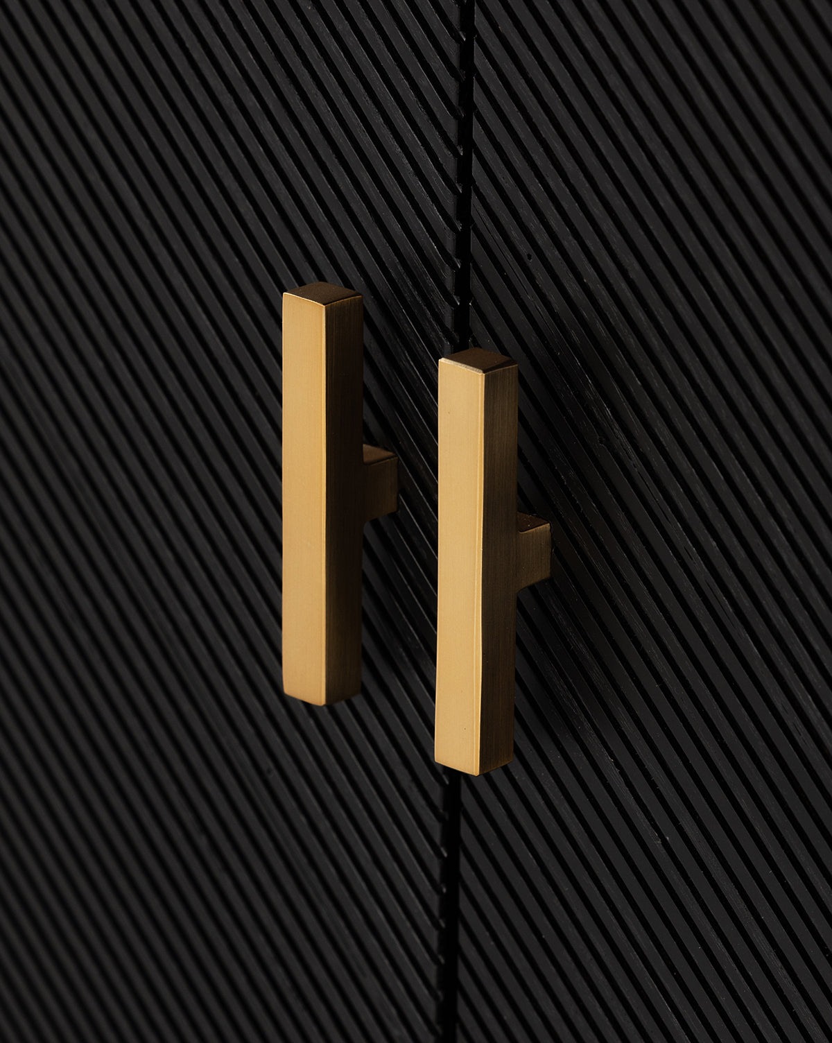 Close-up of two gold rectangular handles on the Ziggy Sideboard, featuring a black ash veneer cabinet door with a diagonal striped texture, by McGee & Co.