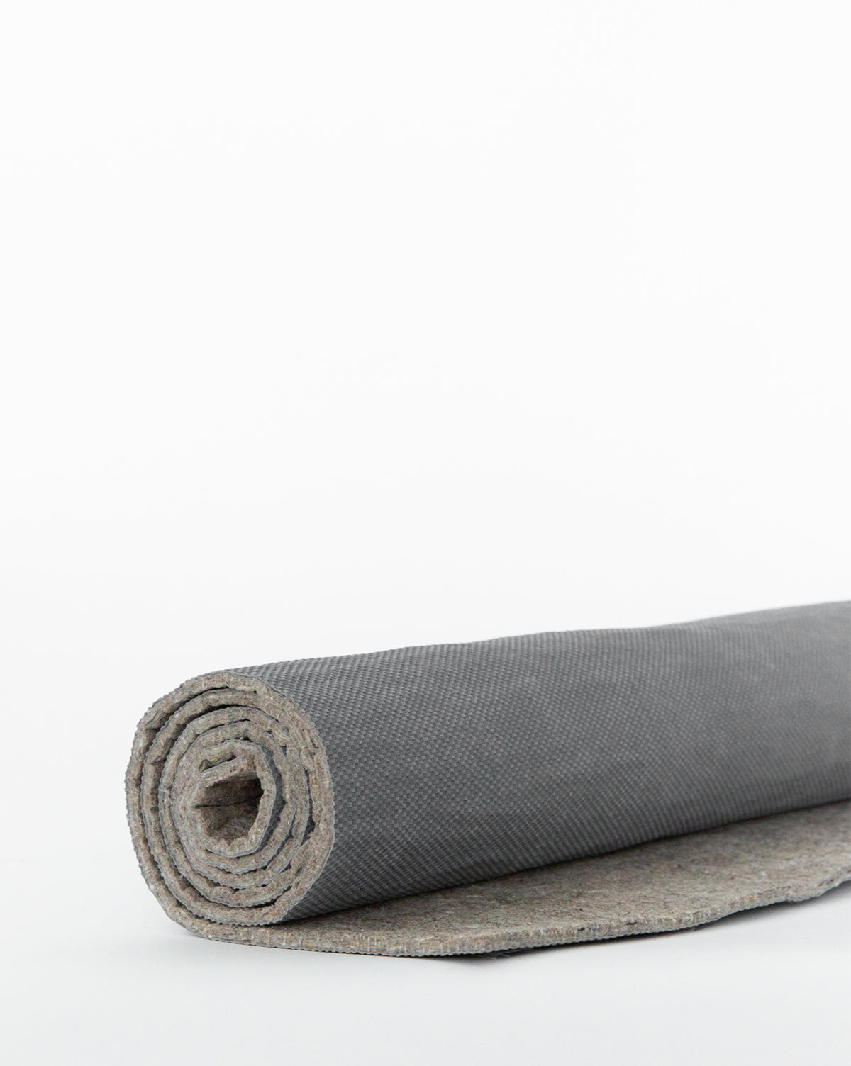 The Premium Indoor Rug Pad, shown partially unrolled on a plain white background, features a textured gray surface and built-in no-slip grip for secure, comfortable use, by McGee & Co.