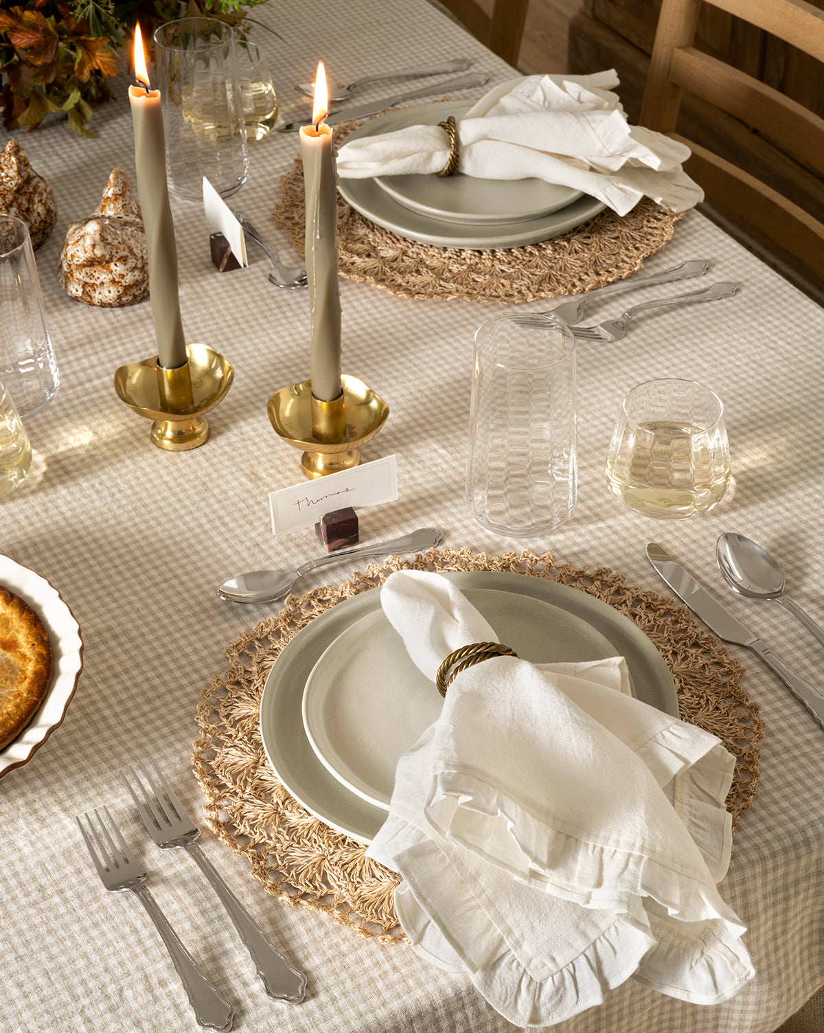 A cozy, elegant table features white plates, cloth napkins with rings, silverware, gold candlesticks with lit candles, a pie on a beige checkered tablecloth, small place cards, autumn decor, and Langford Highball Glasses (Set of 4), by McGee & Co.