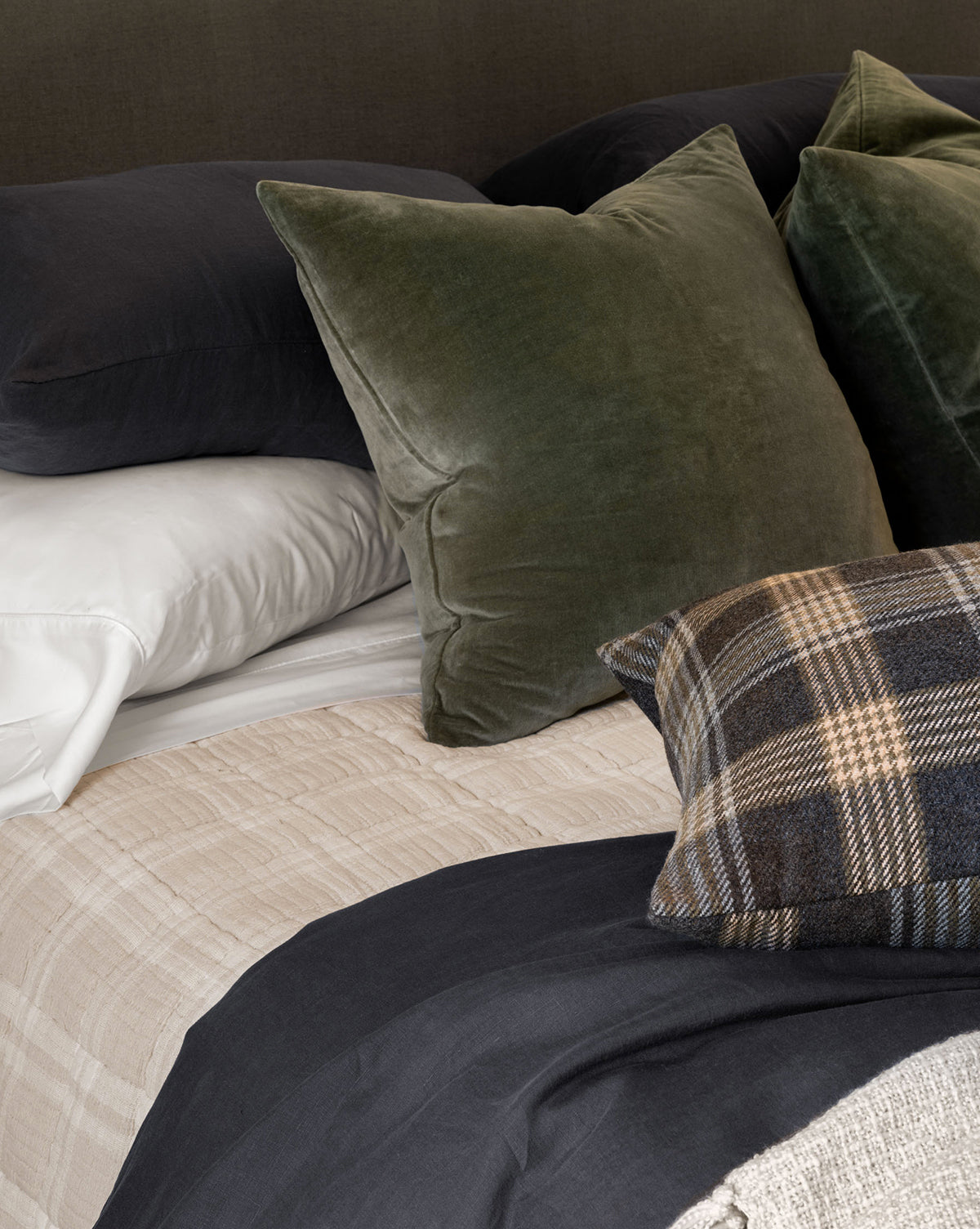 A bed with a soft cotton pillow and a stone washed velvet pillow, both topped with elegant Bellevue Velvet Pillow Covers, by McGee & Co.