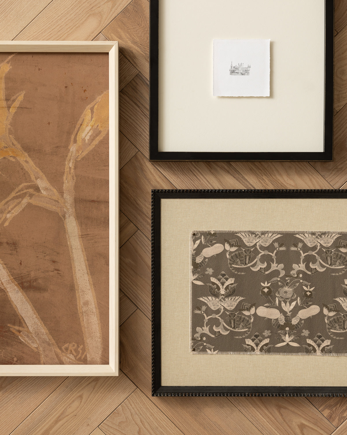 Past Petals, a framed abstract plant artwork in a white wood frame, sits on a light herringbone floor alongside a wide-matted sketch and a floral patterned fabric—ideal as the perfect home accent, by McGee & Co.