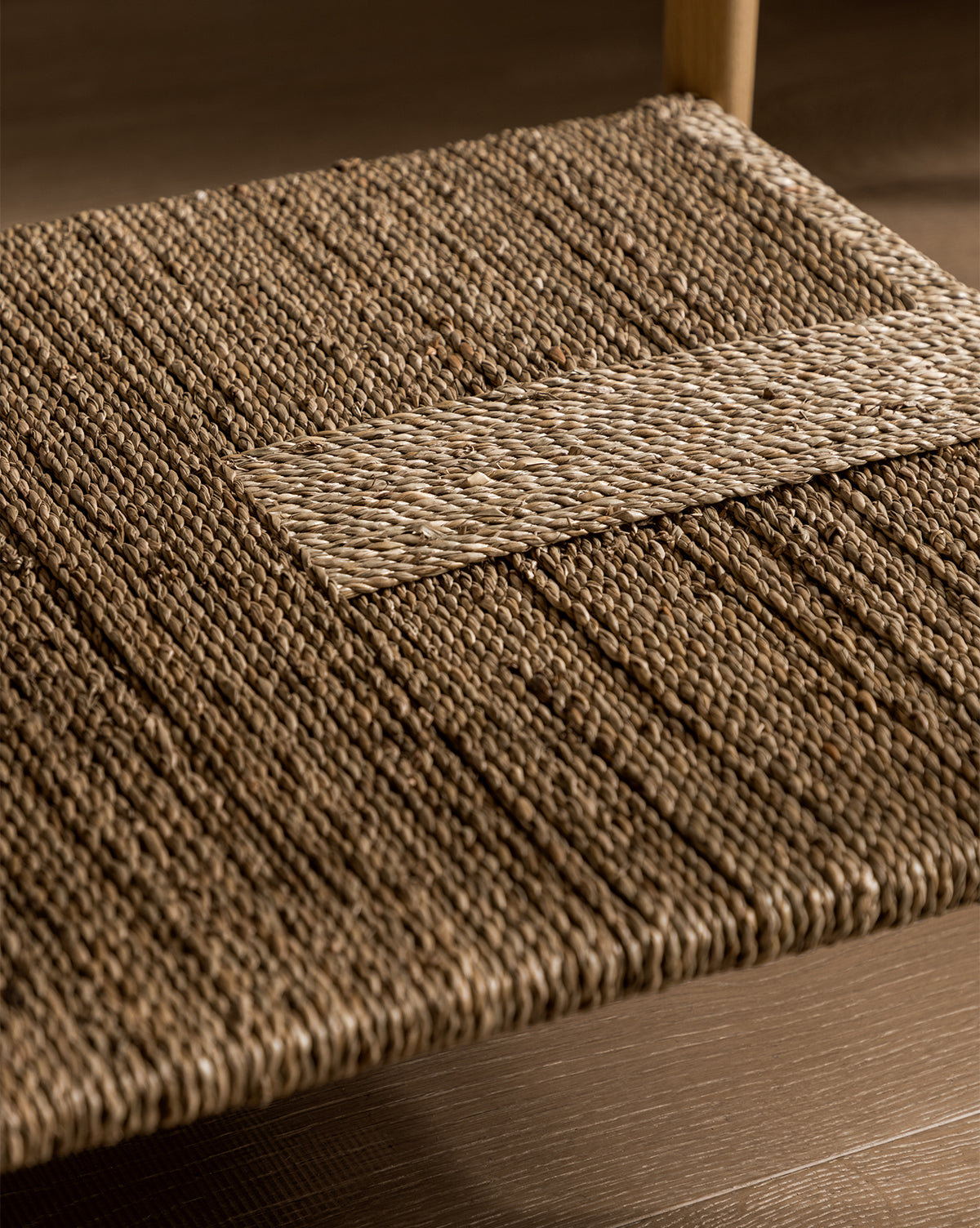 Close-up of the Dana White Oak Nightstand’s woven seagrass shelf, showcasing detailed fiber texture and a rectangular accent in the center, by McGee & Co.