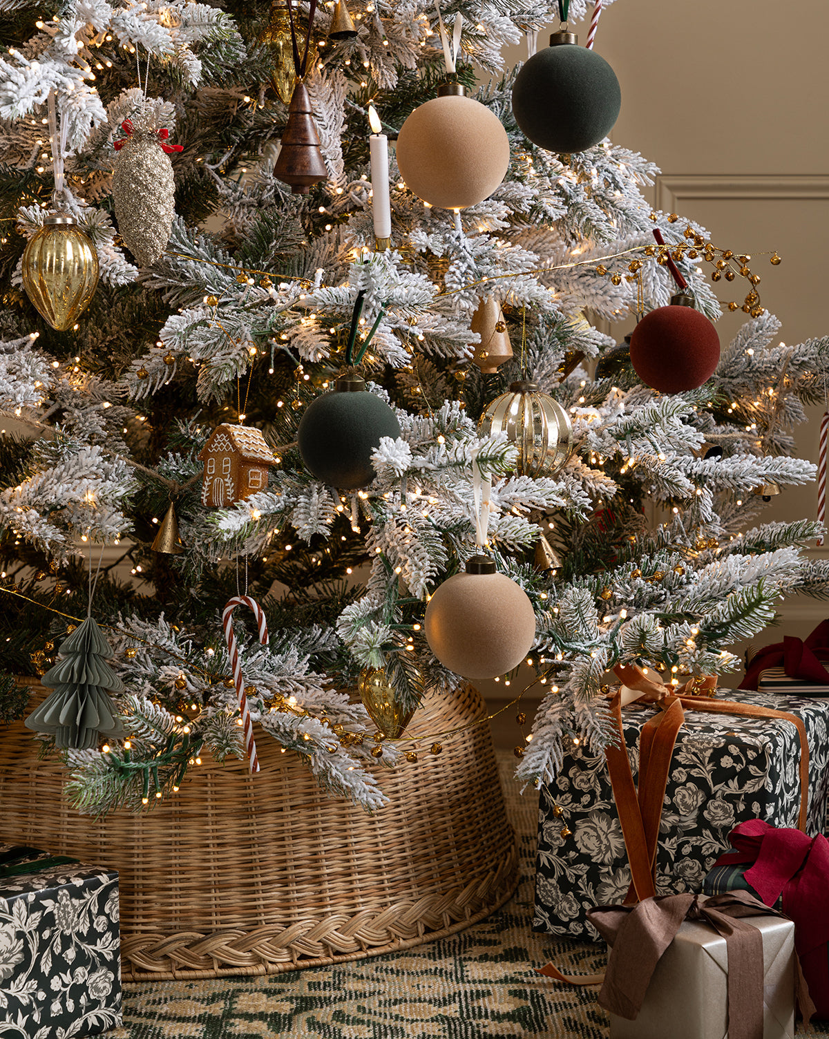 Patterned-wrapped gifts beneath the tree sit in a basket-style collar, completing the holiday decor, by McGee & Co.