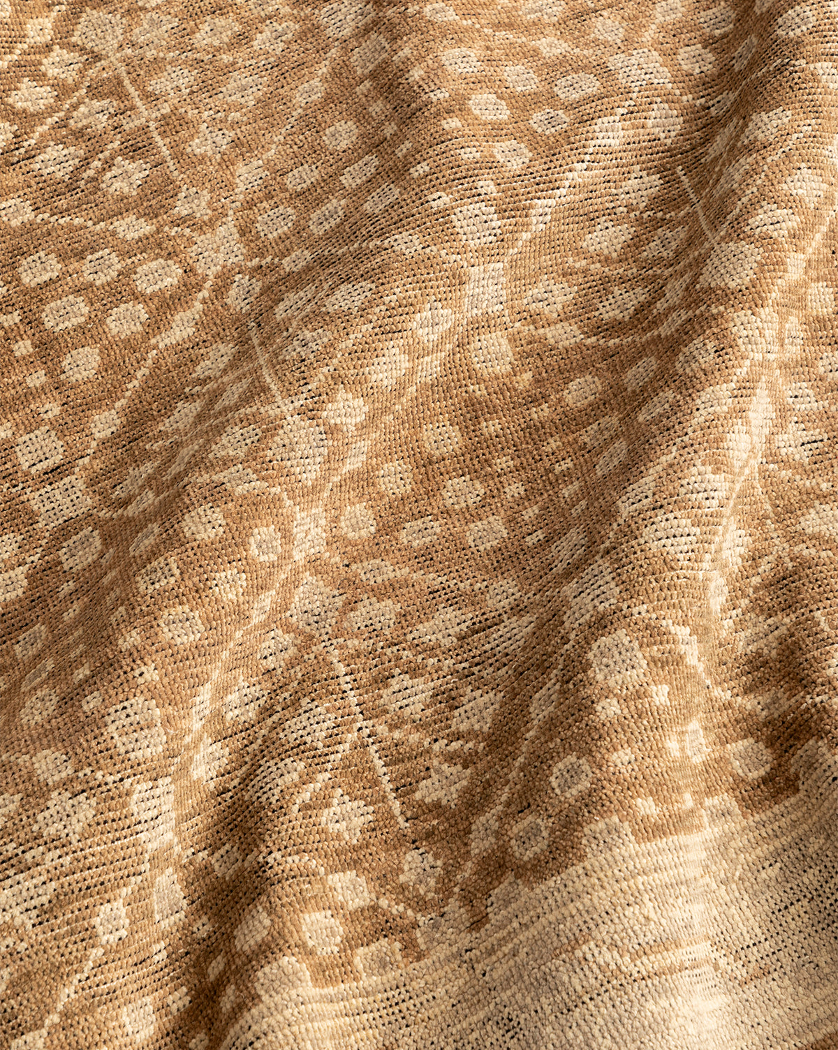 A close-up of the Windsor Hand-Knotted Wool Rug in beige and brown shows its intricate geometric and floral pattern, with subtle folds that highlight the rug's detailed texture and handcrafted design, by McGee & Co.