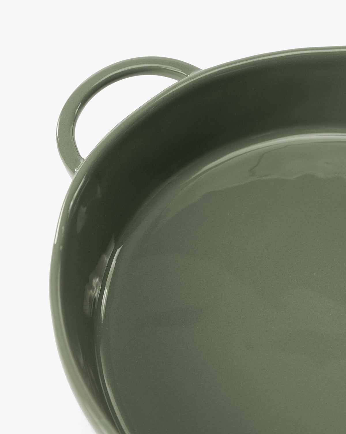 Close-up of a round, glossy green 2 Quart Stoneware Baker (Set of 2) with a left-side handle. The empty dish reflects light on its ceramic surface, by McGee & Co.