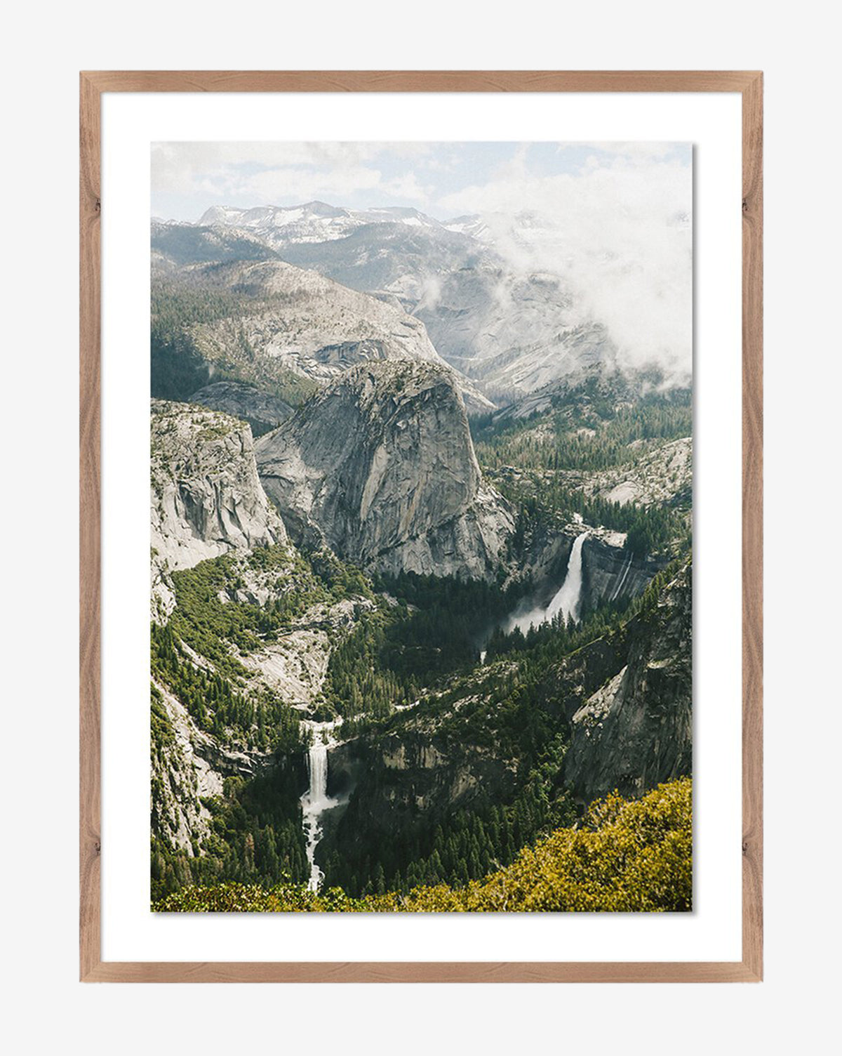 Above The Clouds by Wesley and Emma Teague is a framed photograph featuring a granite peak, lush forests, two waterfalls, and misty clouds in a walnut-finished wood frame for elegant, gallery-quality appeal by McGee & Co.
