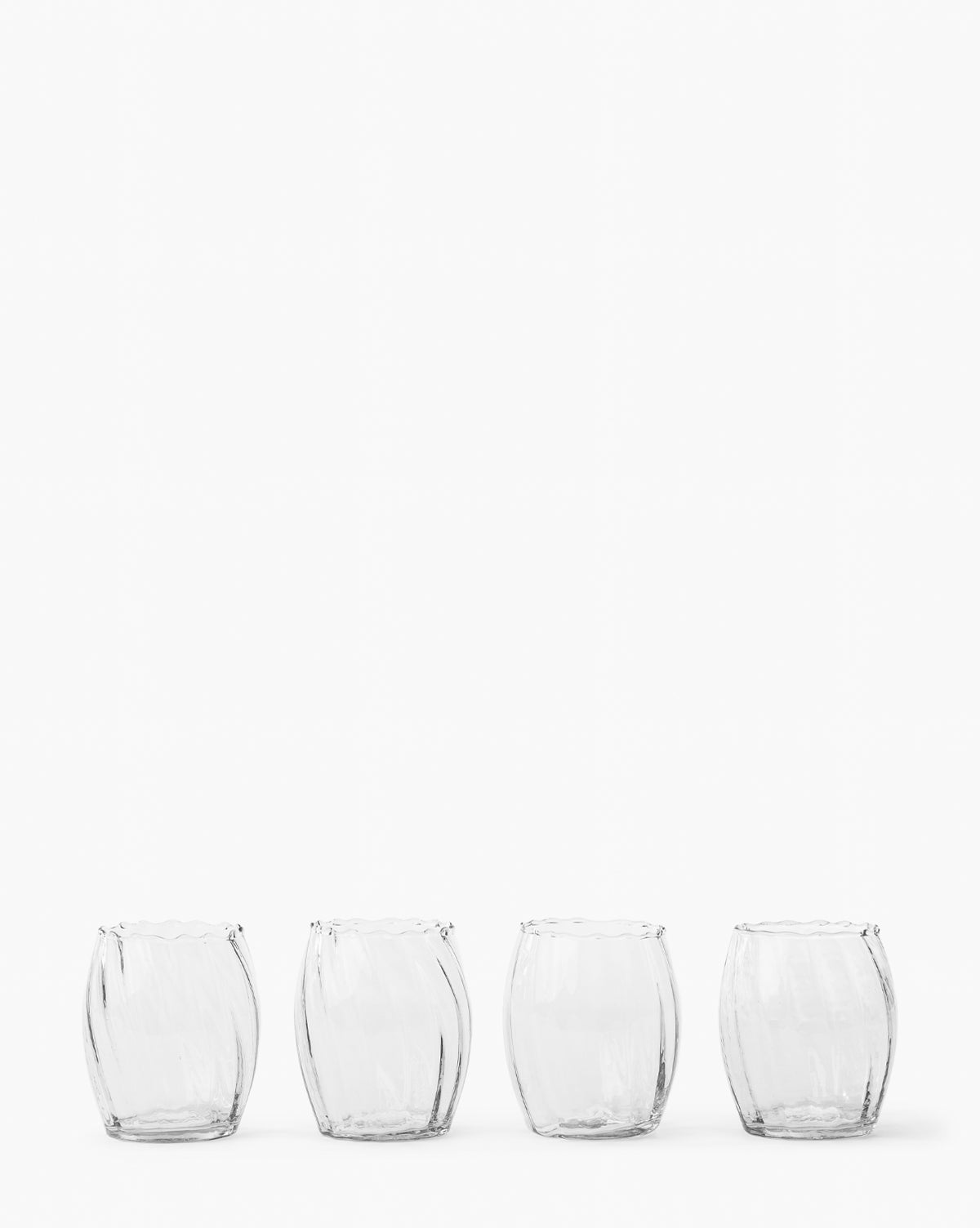 A set of four clear Adderley Tumblers, made from mouth-blown glass with a round, slightly wavy design, are evenly spaced in a horizontal line against a plain white background, by McGee & Co.
