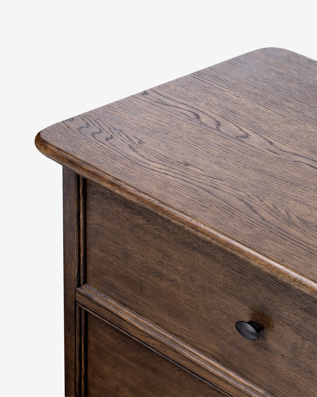 Close-up of the Aeris Nightstand’s top corner showcases its dark brown wood grain finish and a partially open drawer with a round black knob. Ideal for bedroom organization, by McGee & Co. Set against a plain white background.