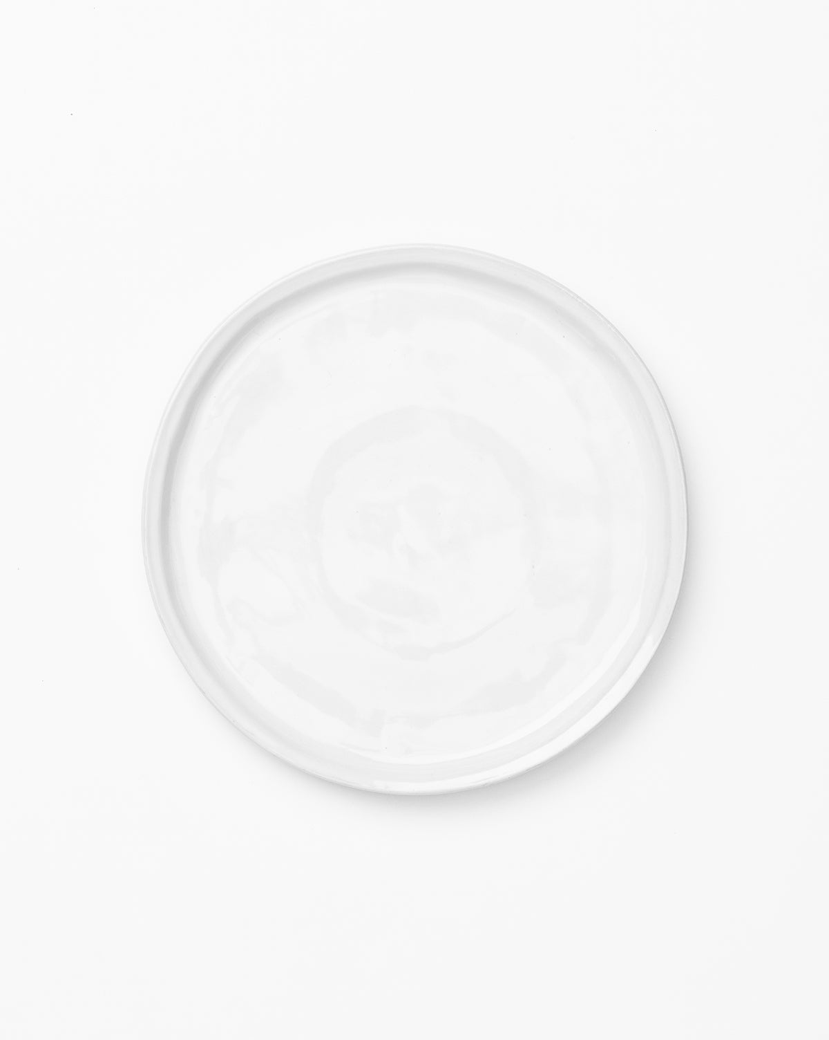 A set of four plain, round, white Aiden Side Plates is photographed from above on a white background, by McGee & Co.