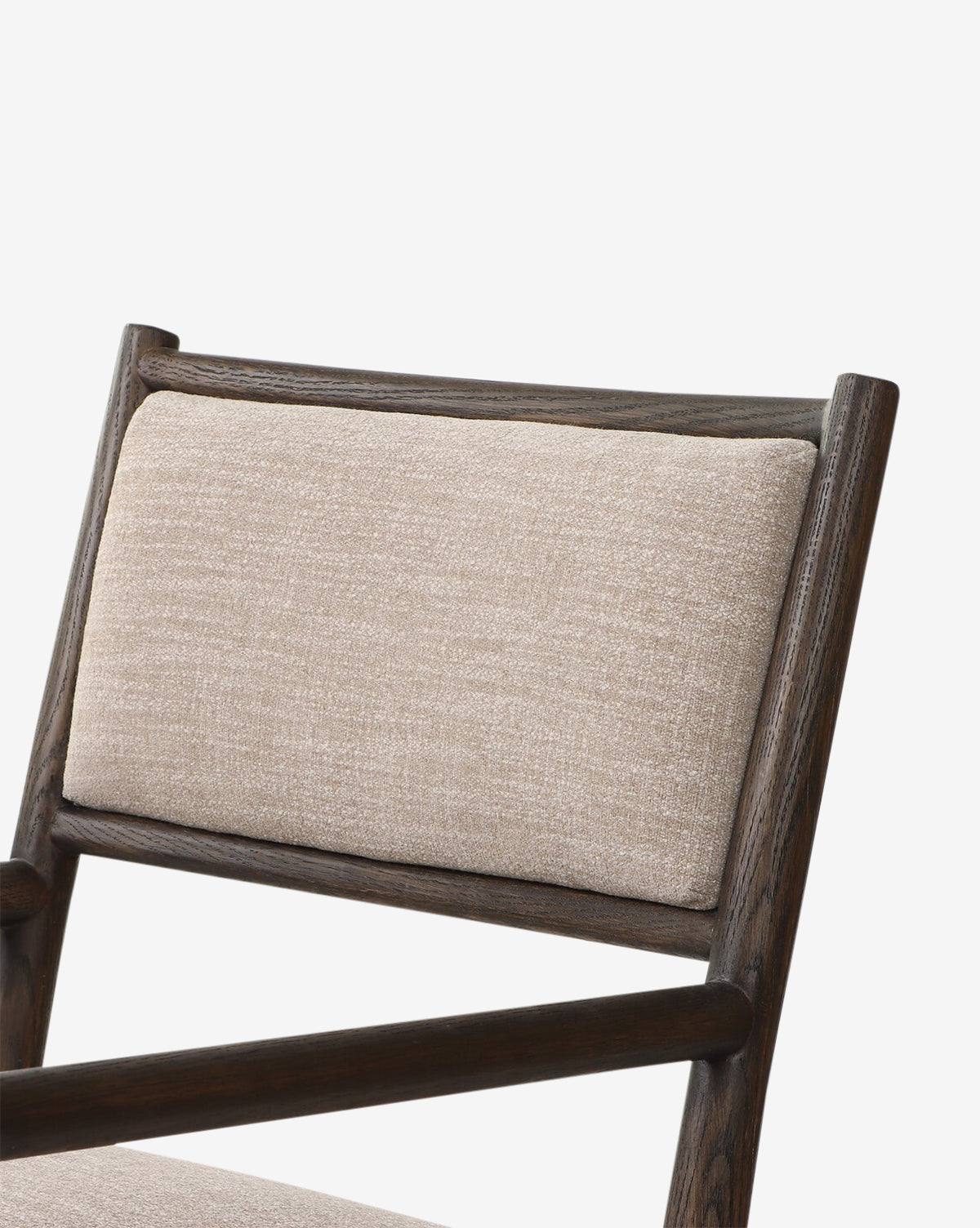 Close-up of the Ailsa Dining Chair, a modern piece with a dark oak frame and beige upholstered backrest, shown against a plain white background, by McGee & Co.