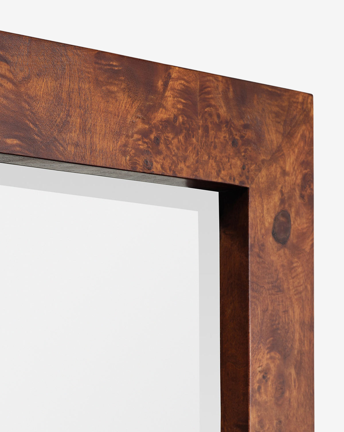 Close-up of the top corner of the Alexia Rectangular Mirror, featuring a thick, polished brown burl wood frame with a natural grain pattern. Set against a plain white background—an ideal unique statement piece for any space, by McGee & Co.