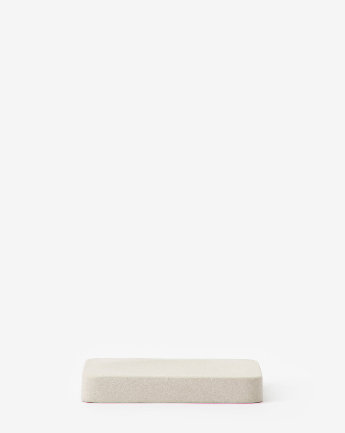 A rectangular, light beige cushion from the Amada Sandstone Bath Collection sits centered on a white background, adding an organic touch that complements modern bathroom decor.