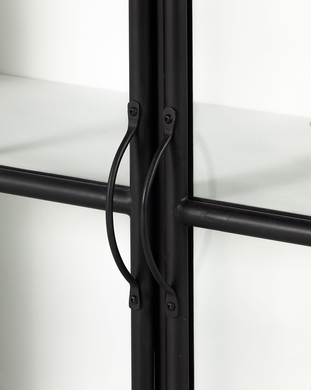 Close-up of two black metal handles on the Amalie Sideboard’s glass cabinet door, featuring a black metal frame, crossbars, and frosted glass panels—perfect for stylish storage.