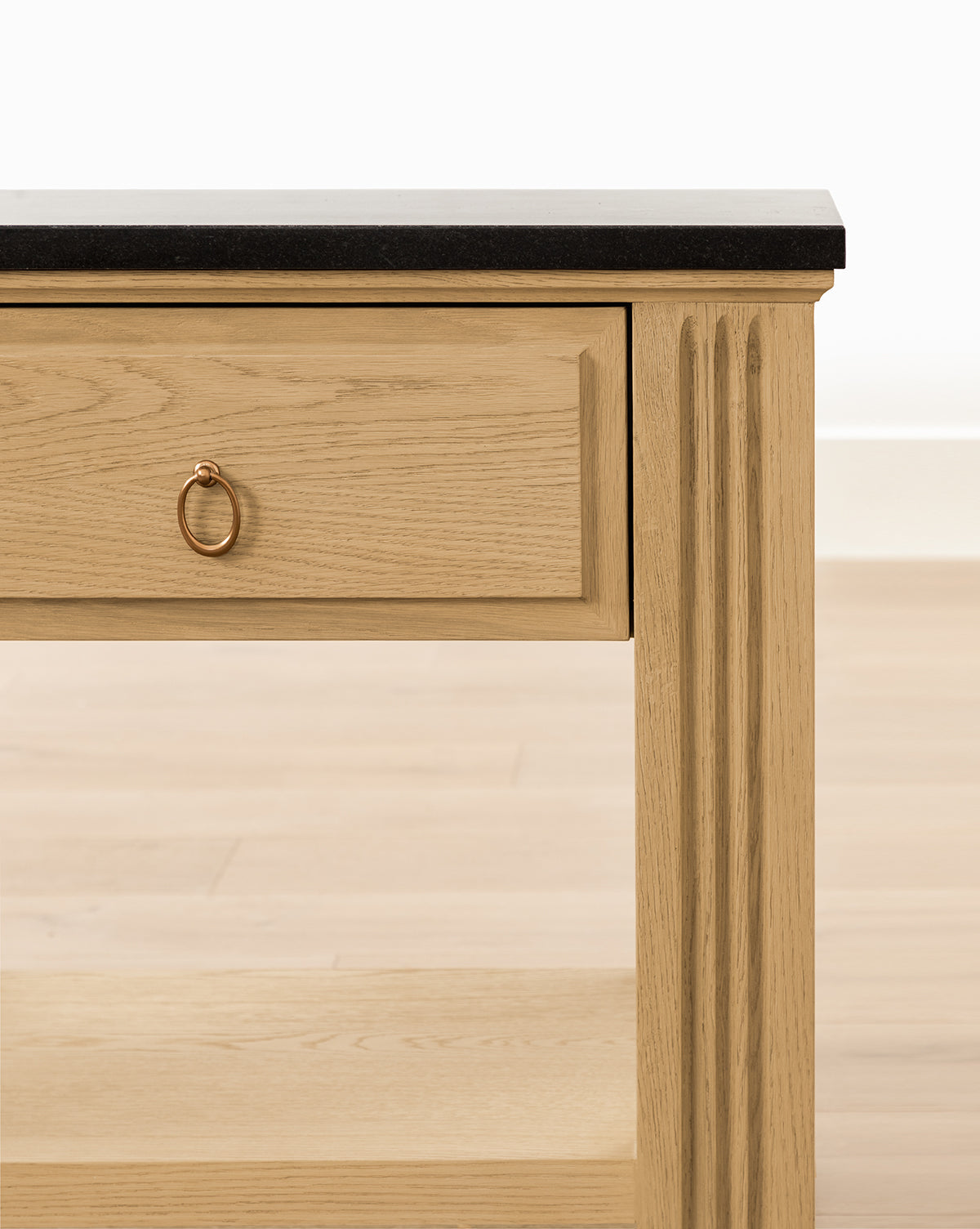 Close-up of the Ambrose Nightstand with a honed granite top, single drawer with a round gold handle, vertical side grooves, and lower shelf; set against a light background—modern style meets vintage inspiration, by McGee & Co.