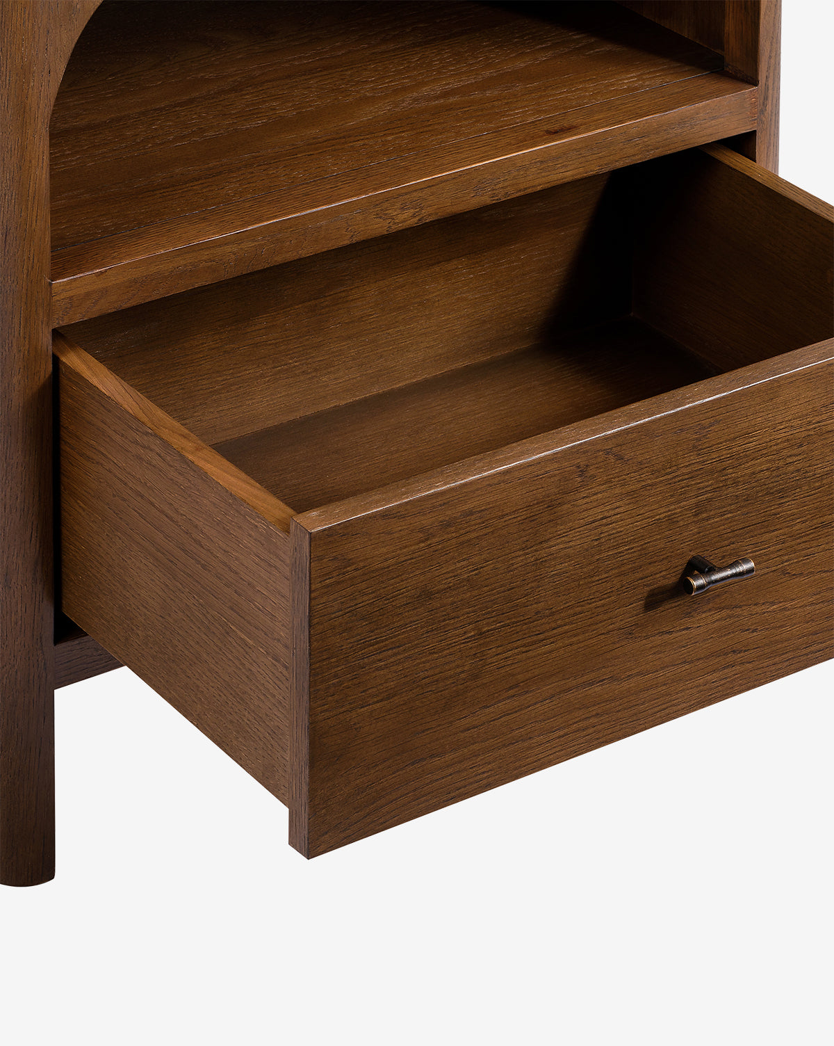 A close-up of the Ambrosia Nightstand shows its single drawer partially open, revealing the interior. The walnut oak veneer has a rich brown finish, accented by an antique brass handle, by McGee & Co.