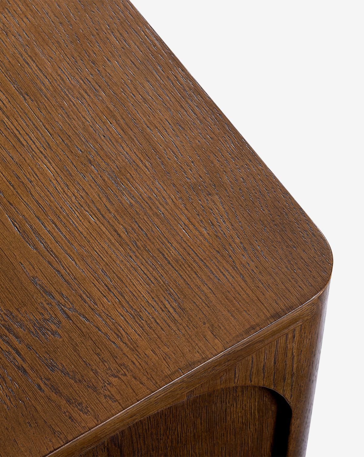 Close-up of the Ambrosia Nightstand’s corner, featuring a smooth, polished walnut oak veneer with visible wood grain, rounded edges, and a rich brown finish by McGee & Co.