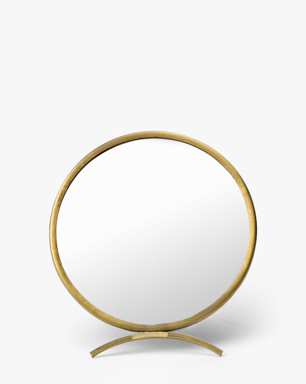 The Antique Brass Folding Mirror features a round design, a brass-finished frame, and a curved gold stand, displayed against a plain white background by McGee & Co.