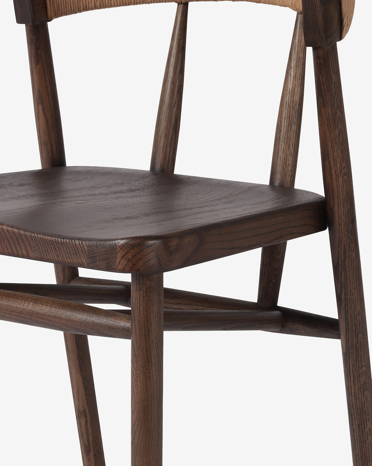 Close-up of the Four Hands Ardent Stool showcases its solid oak frame, dark smooth seat, angled legs, and curved backrest. The modern design and natural wood grain finish make it perfect for any kitchen bar setting. McGee & Co.