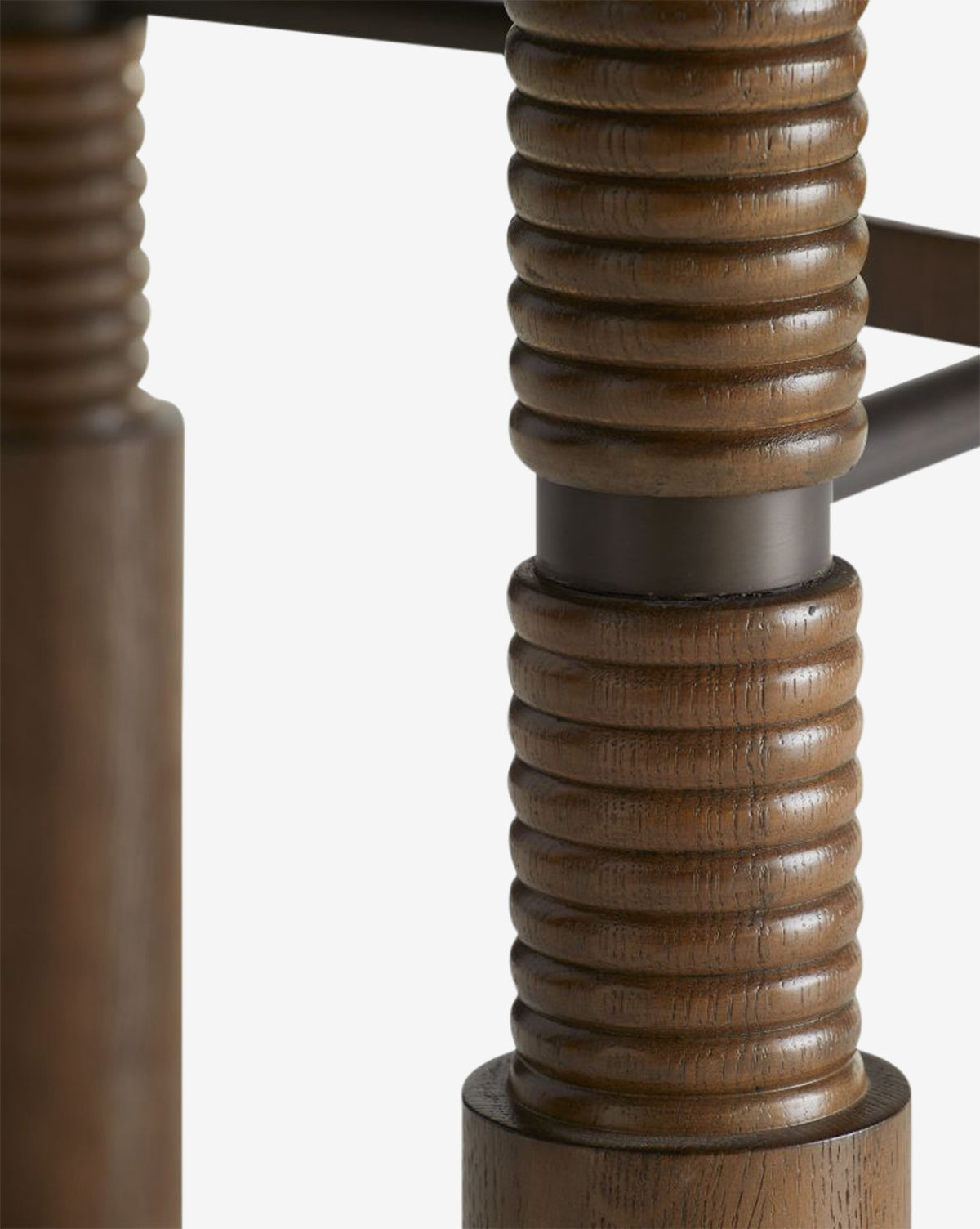 Close-up of Ashford Dining Table legs featuring oak veneer, dark metal accents, and a ridged, grooved texture, evoking vintage style against a white background, by McGee & Co.