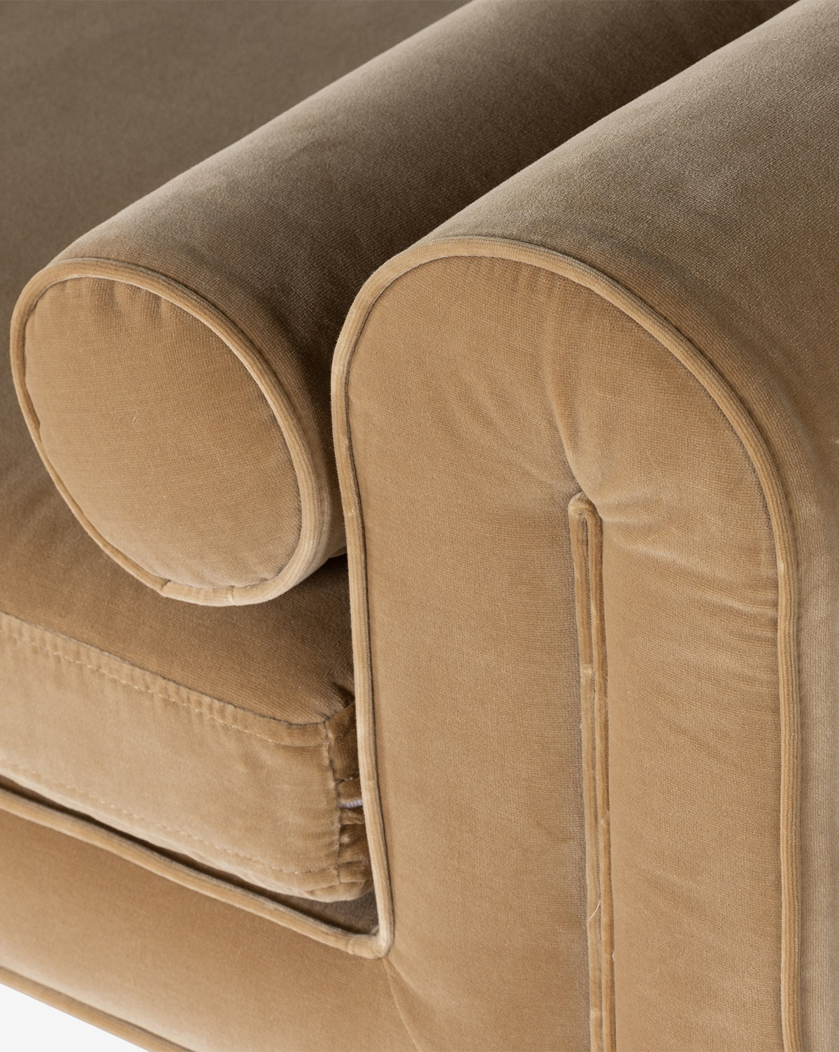 A close-up of the tan velvet sofa’s armrest and cylindrical bolster pillow with piped edges, its plush fabric accentuating a modern look—perfect to pair with the Ashlyn Bench or other upholstered benches, by McGee & Co.
