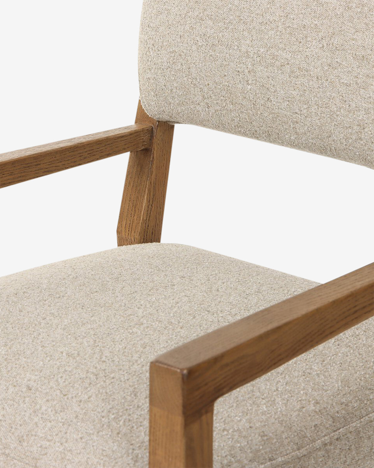 A close-up of the Bailey Dining Arm Chair shows its light beige upholstered seat and backrest, complemented by smoked oak wooden armrests and frame, by McGee & Co.