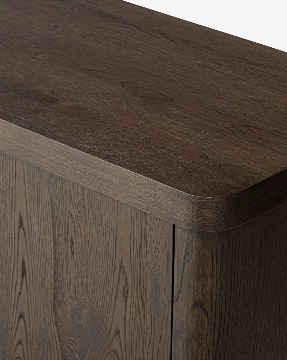 A close-up of the Baldwin Sideboard shows its smooth, rounded top corner and rich wood grain on the top and side panels, highlighting its elegant craftsmanship by McGee & Co.