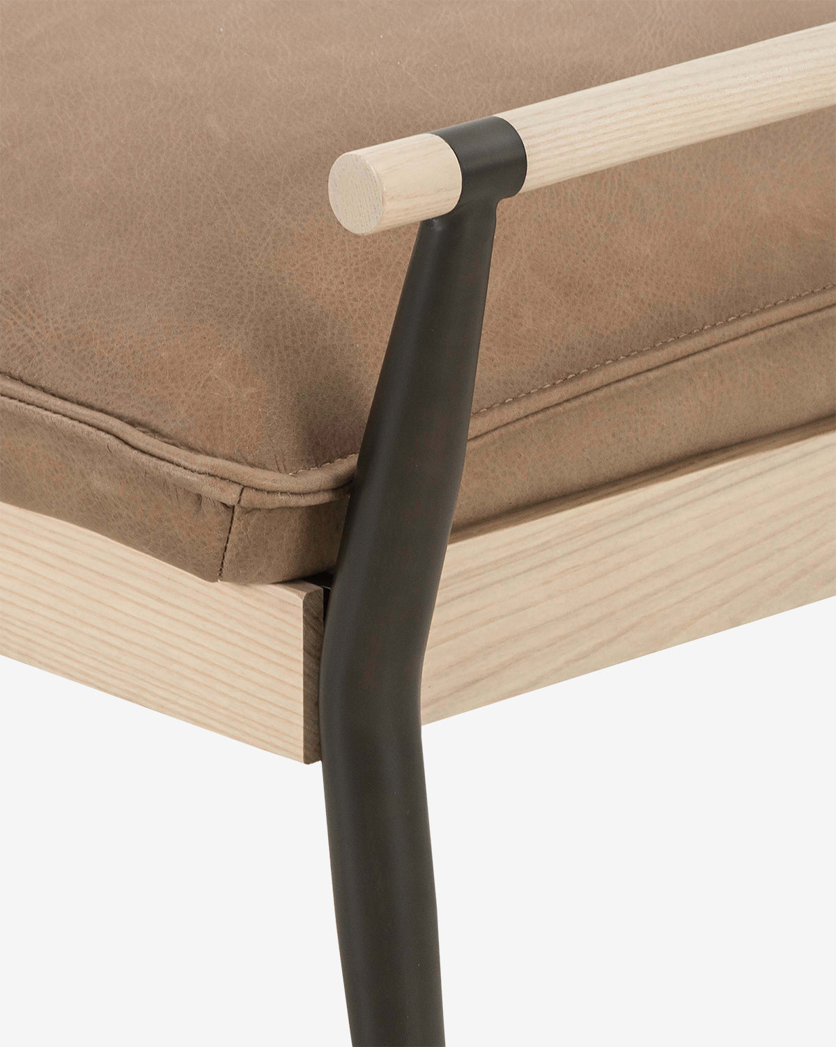 Close-up view of the Balfour Bench, featuring an upholstered brown leather cushion, a light wood frame, and a black metal support topped with a matching light wood armrest, by McGee & Co.