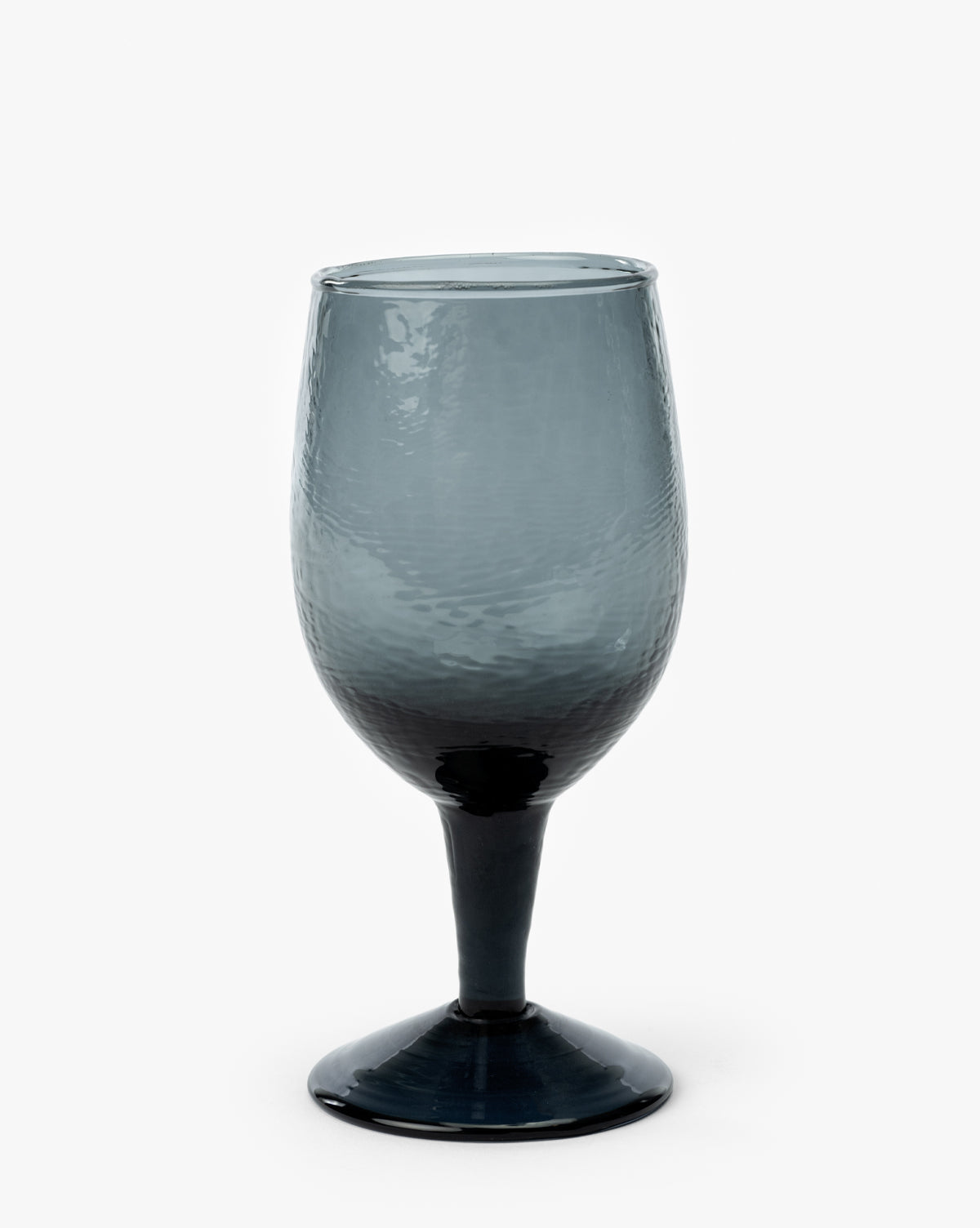 The Ballina Wine Glass features a dark gray, smoke finish with a rounded bowl and short stem, offering a modern touch to any table. Shown here as a single glass on a plain white background by McGee & Co.