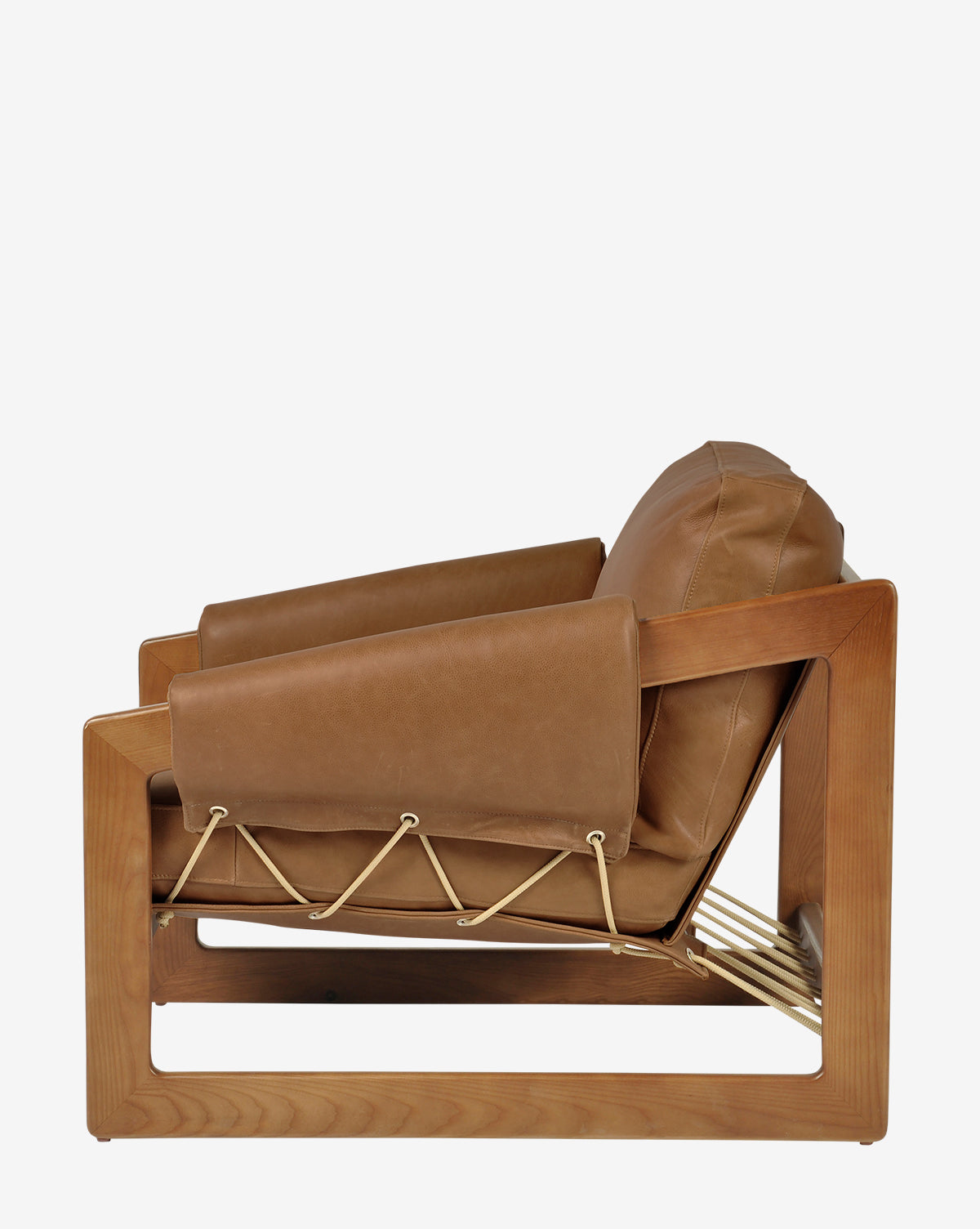 Side view of the Barker Lounge Chair, a modern armchair with a wooden frame, tan top-grain leather cushions, and rope accents inspired by classic midcentury sling seating, by McGee & Co.