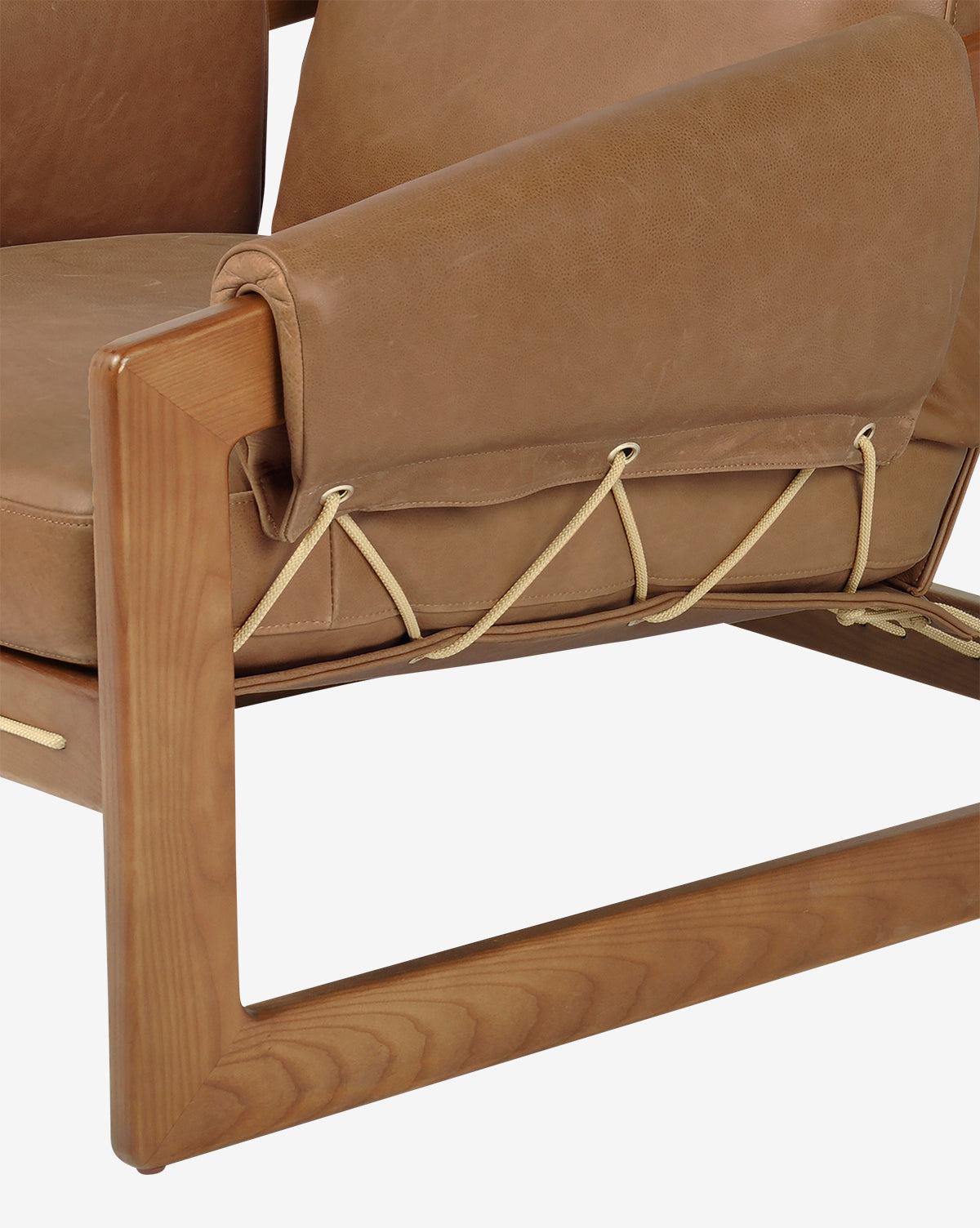 Close-up of the Barker Lounge Chair, featuring a wooden frame, top-grain leather cushions, and beige cord lacing on the armrest and seat, showcasing its craftsmanship and midcentury sling seating style, by McGee & Co.