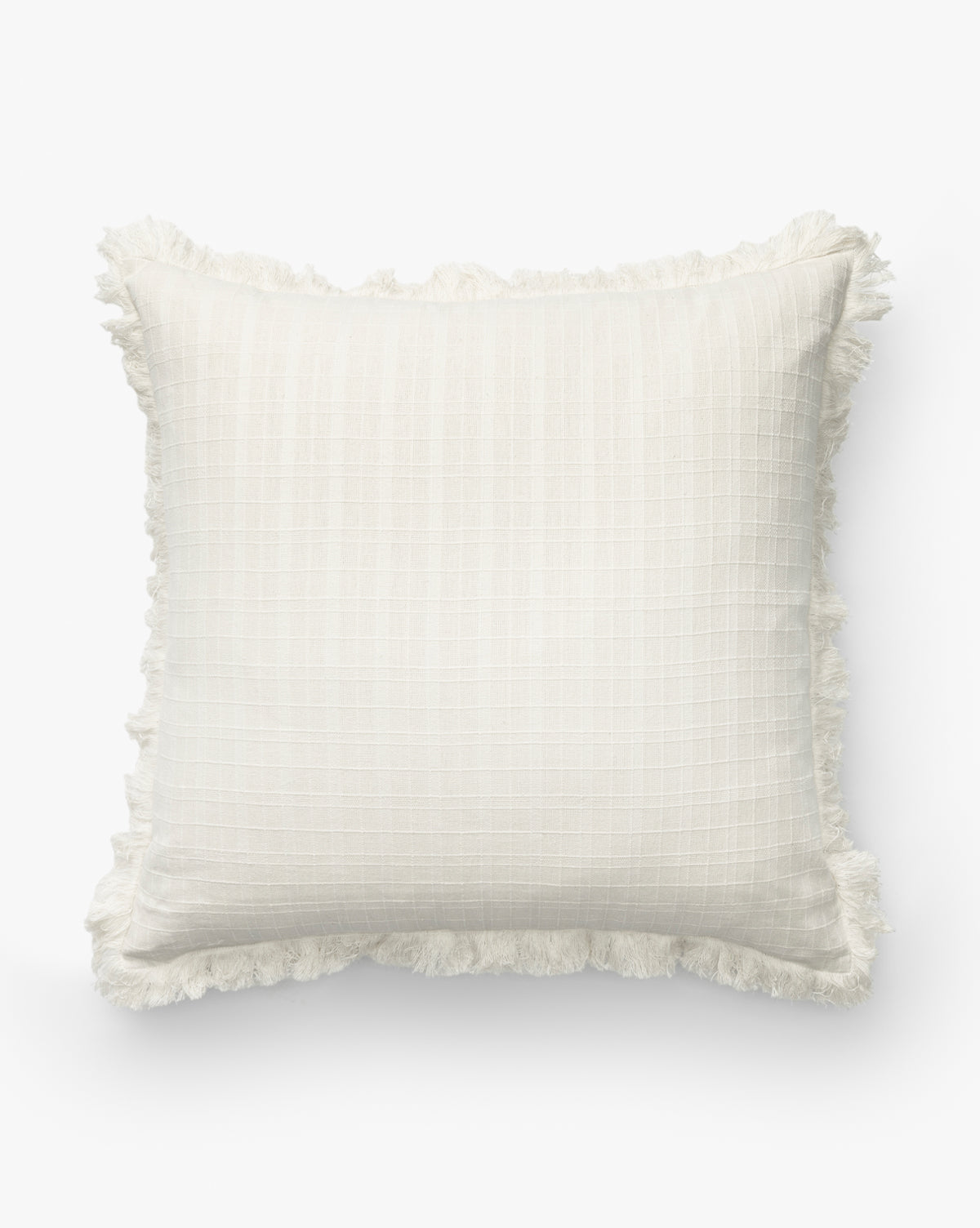 The Barnes Pillow Cover is a square, off-white decorative cover featuring a subtle checkered pattern and fringe trim on the edges, displayed against a plain white background by McGee & Co.